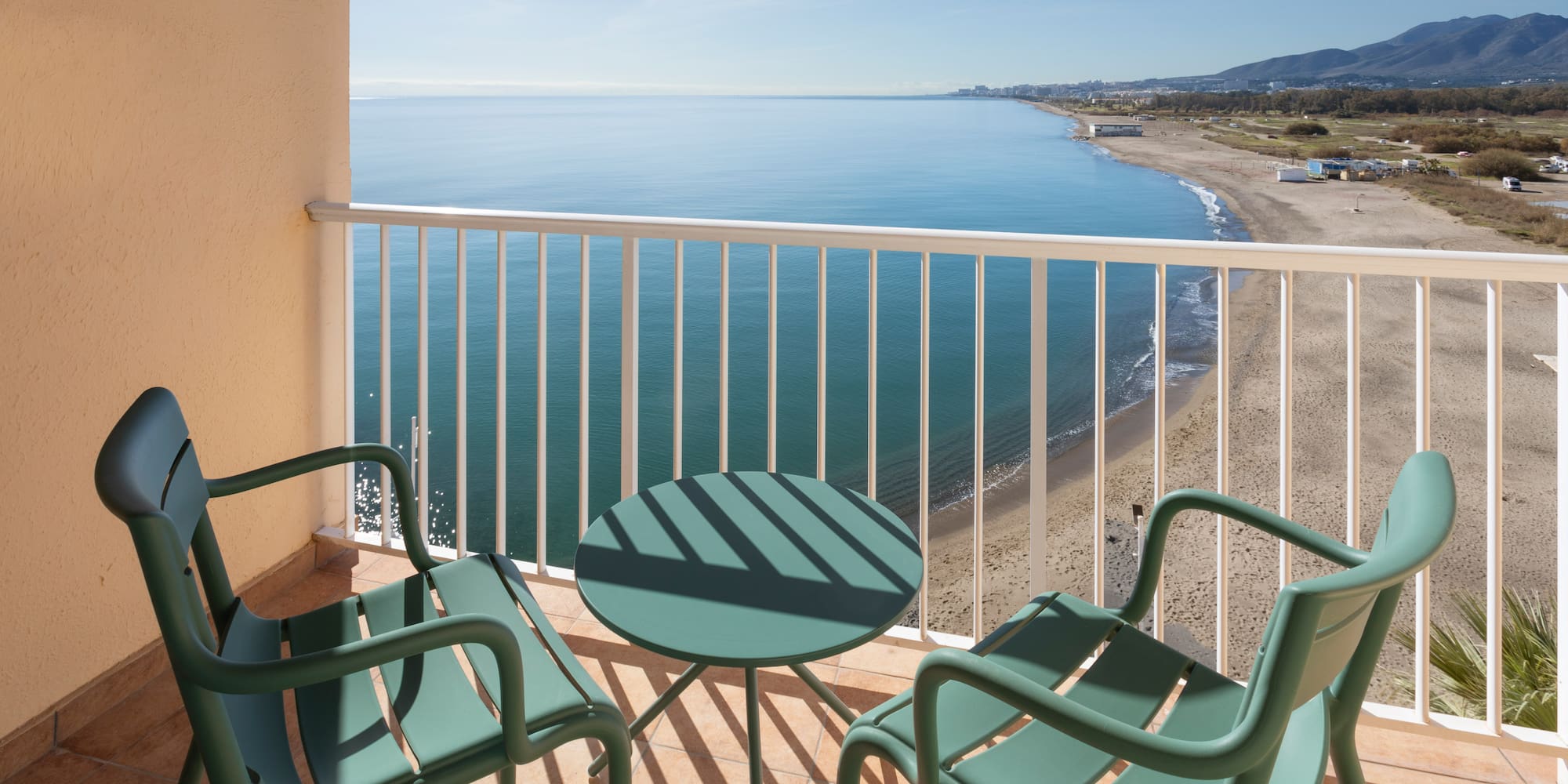 a balcony with chairs and a table overlooking the ocean