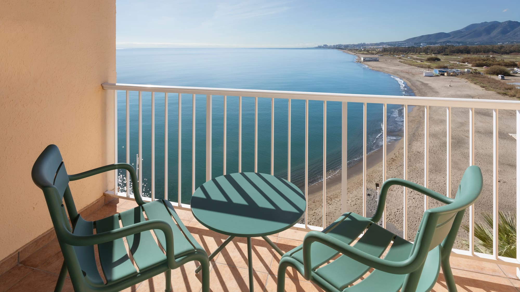 a balcony with chairs and a table overlooking the ocean