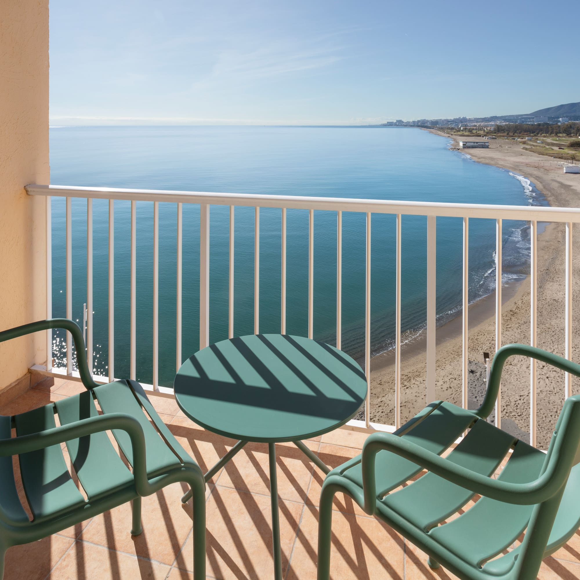 a balcony with chairs and a table overlooking the ocean
