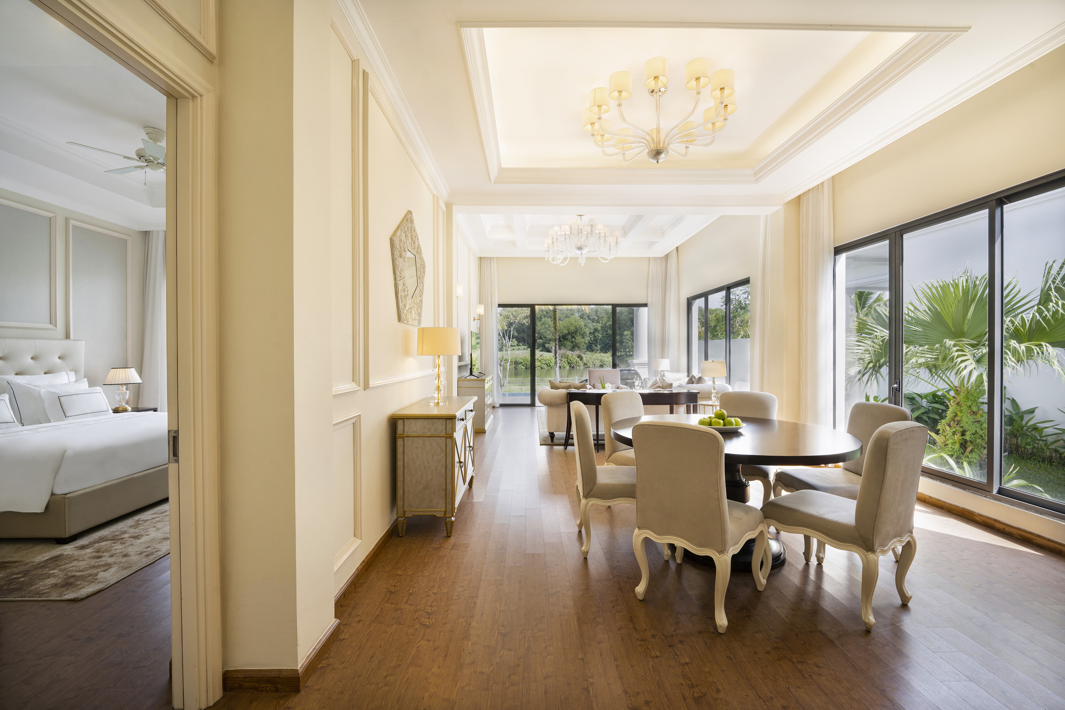 Elegant hotel suite with dining, living room, bedroom, and garden view.