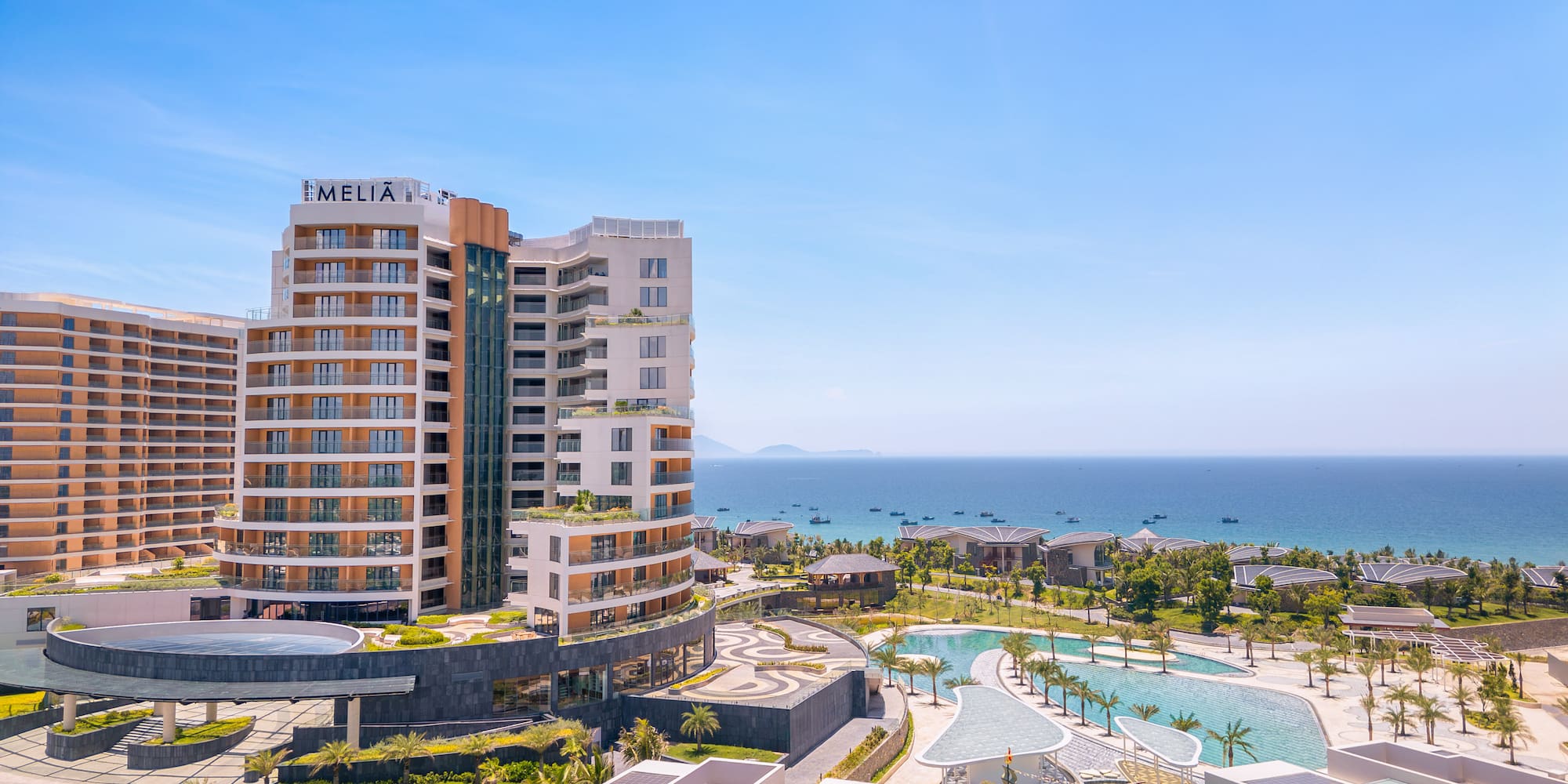Melia resort and hotel overlooking ocean with pools and palm trees.