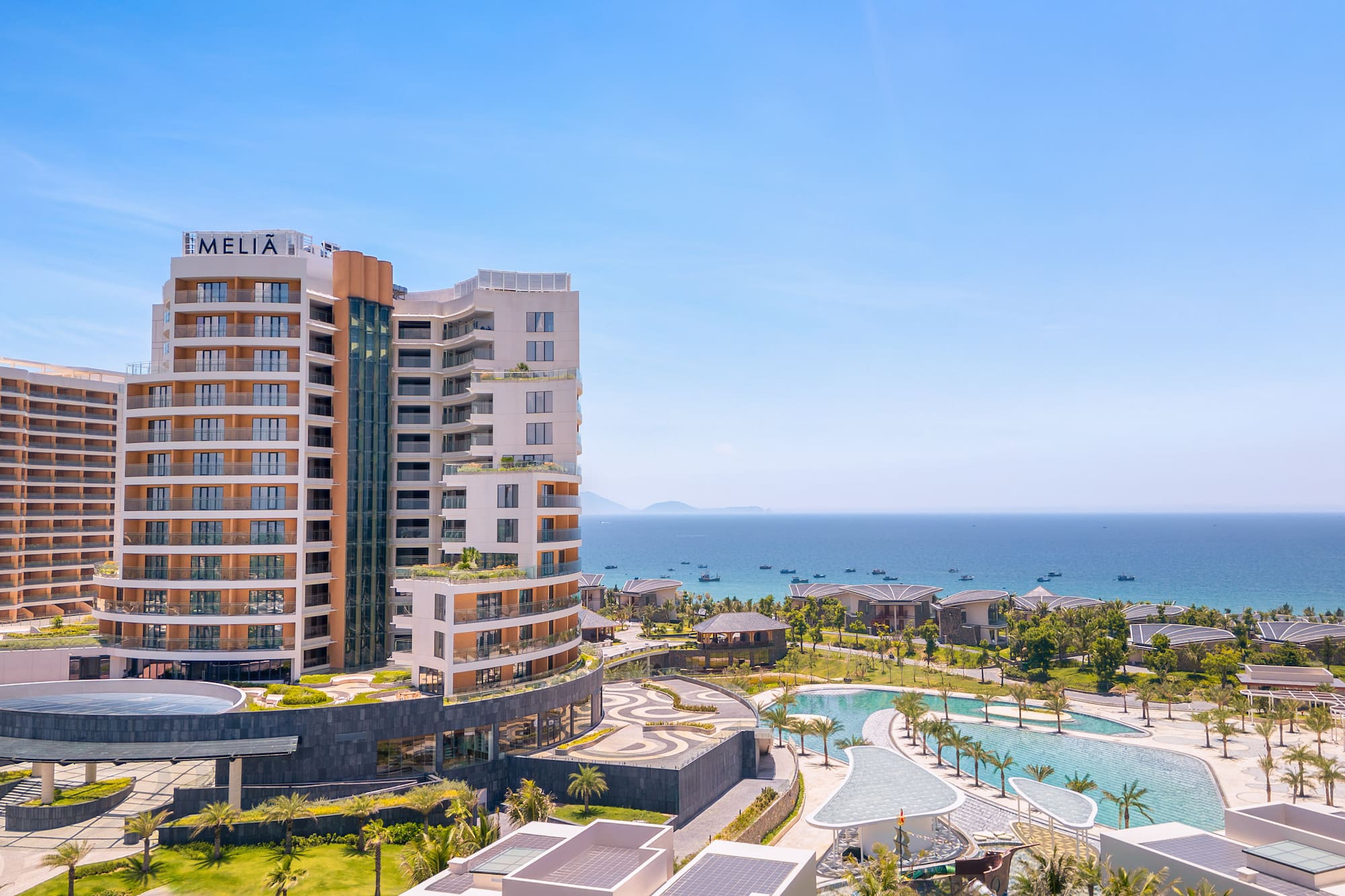 Melia resort and hotel overlooking ocean with pools and palm trees.