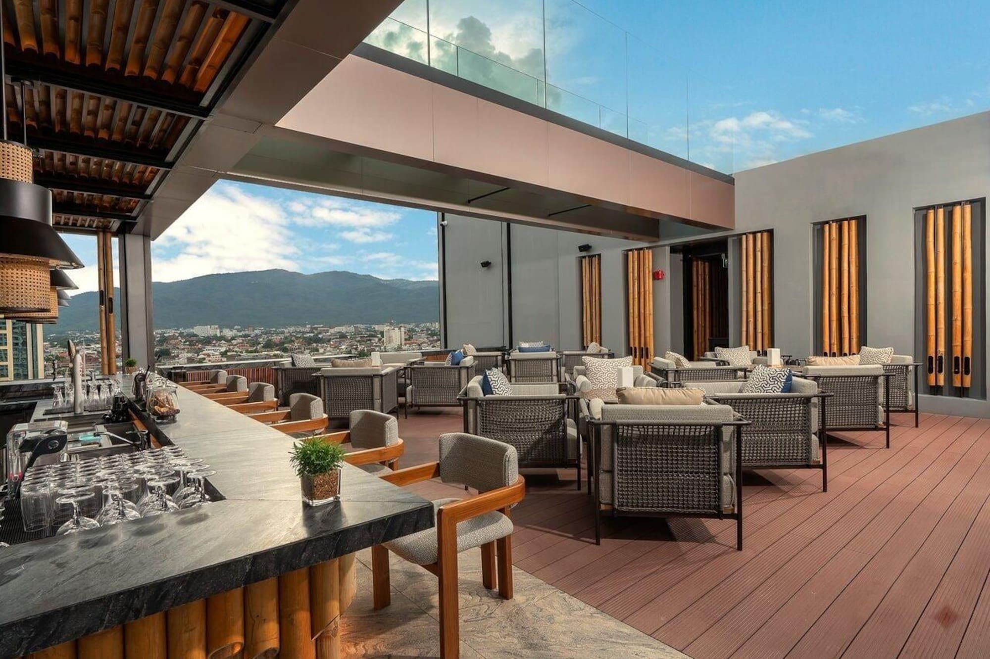 Rooftop bar and lounge with modern seating, city, and mountain views.