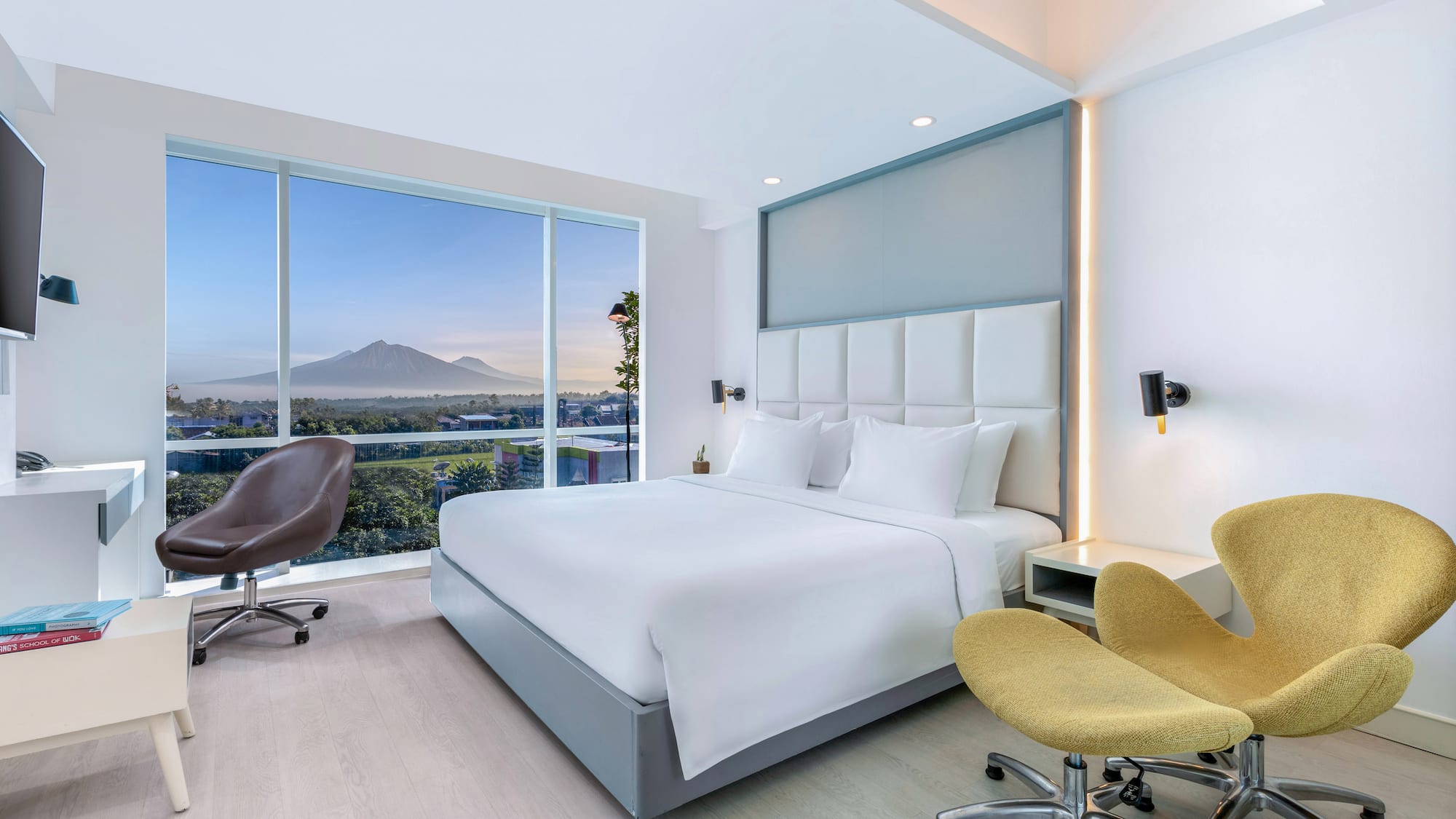 a room with a bed and chairs and a large window