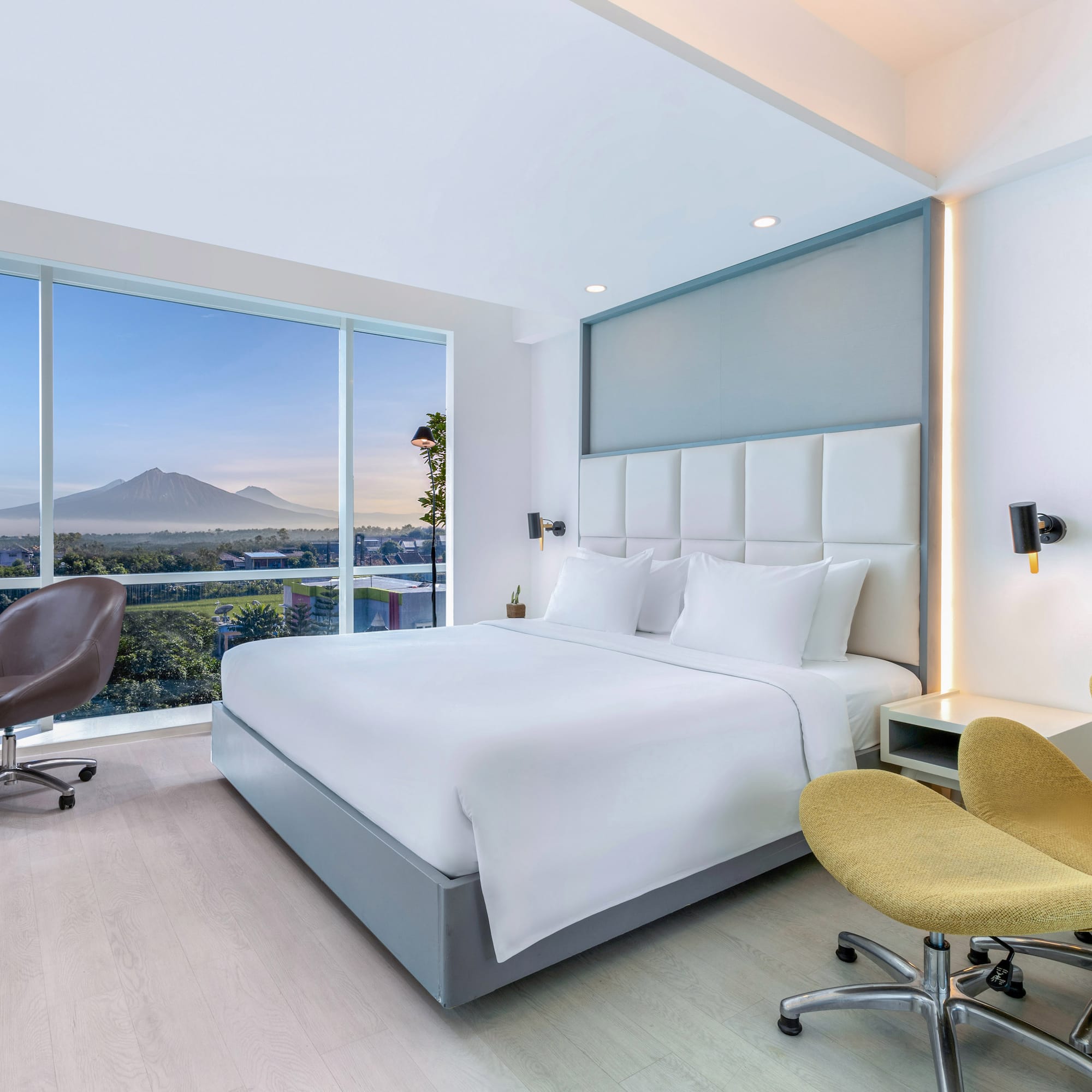 a room with a bed and chairs and a large window