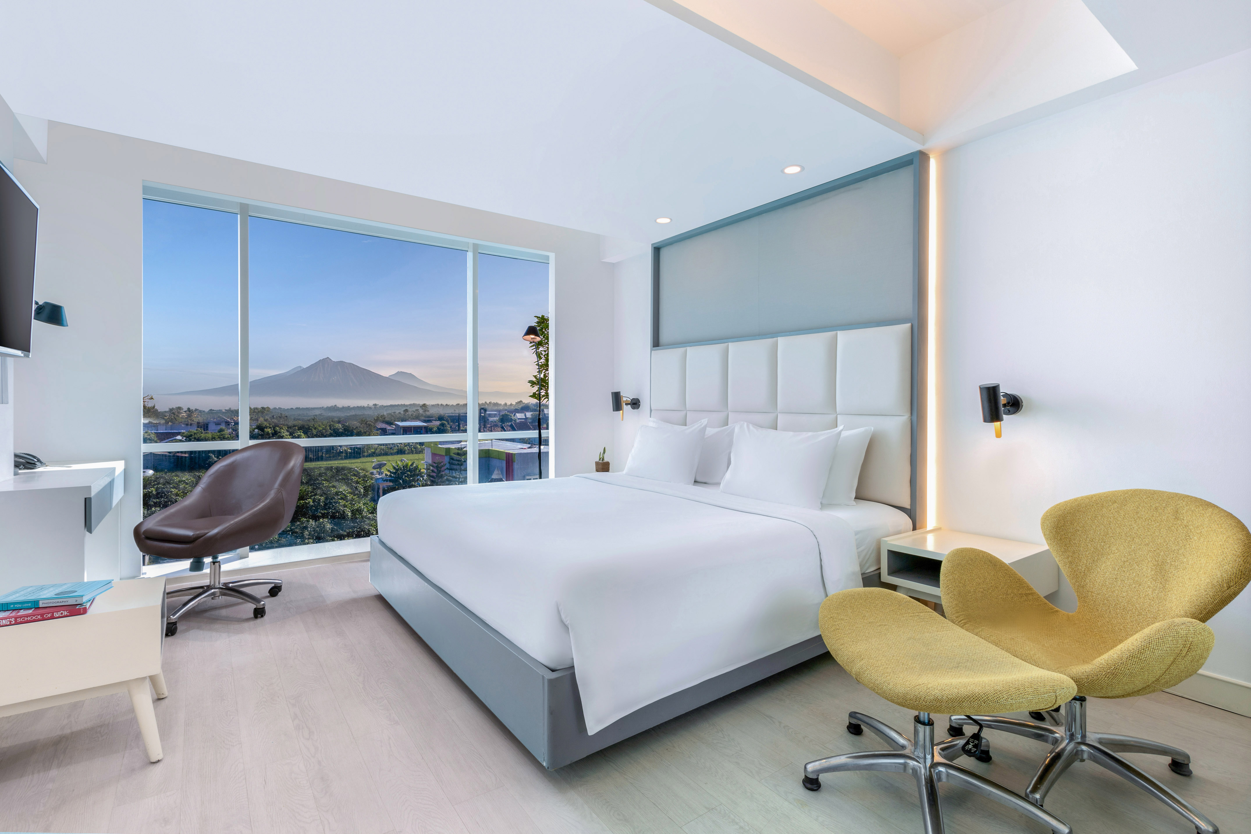 a room with a bed and chairs and a large window