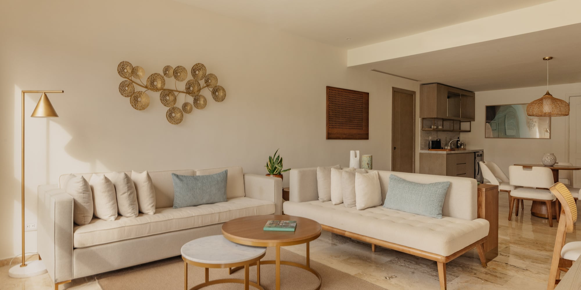 Modern living room with neutral sofas, nesting coffee tables, gold wall art.