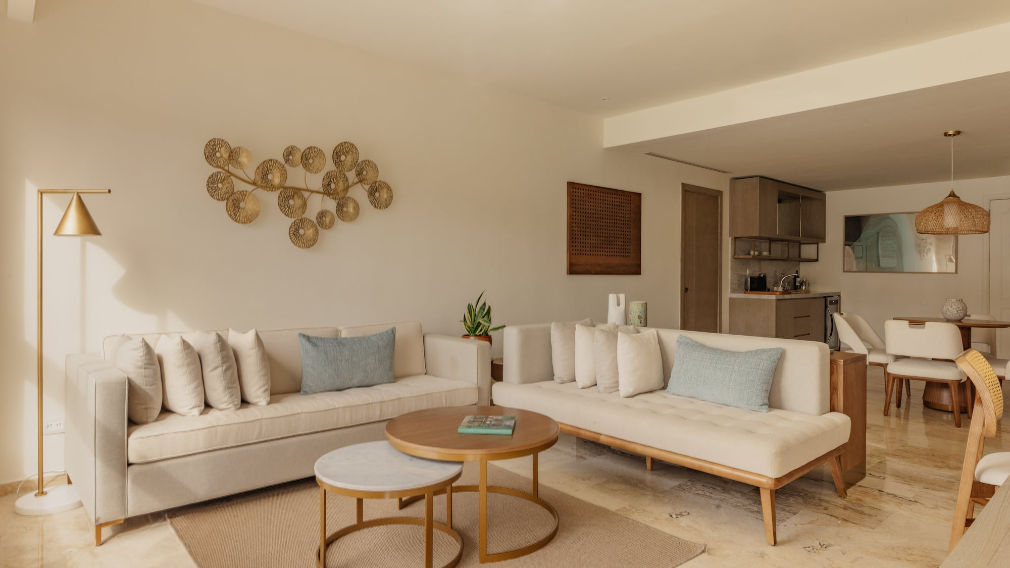 Modern living room with neutral sofas, nesting coffee tables, gold wall art.