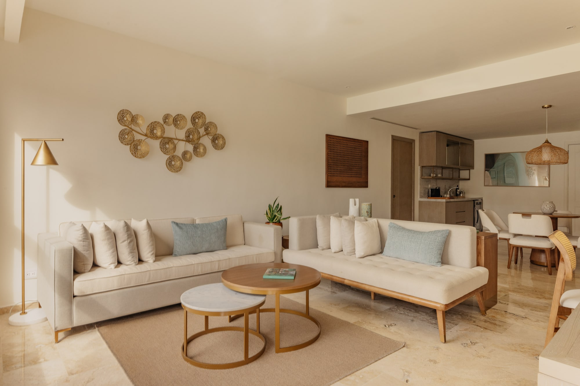 Modern living room with neutral sofas, nesting coffee tables, gold wall art.