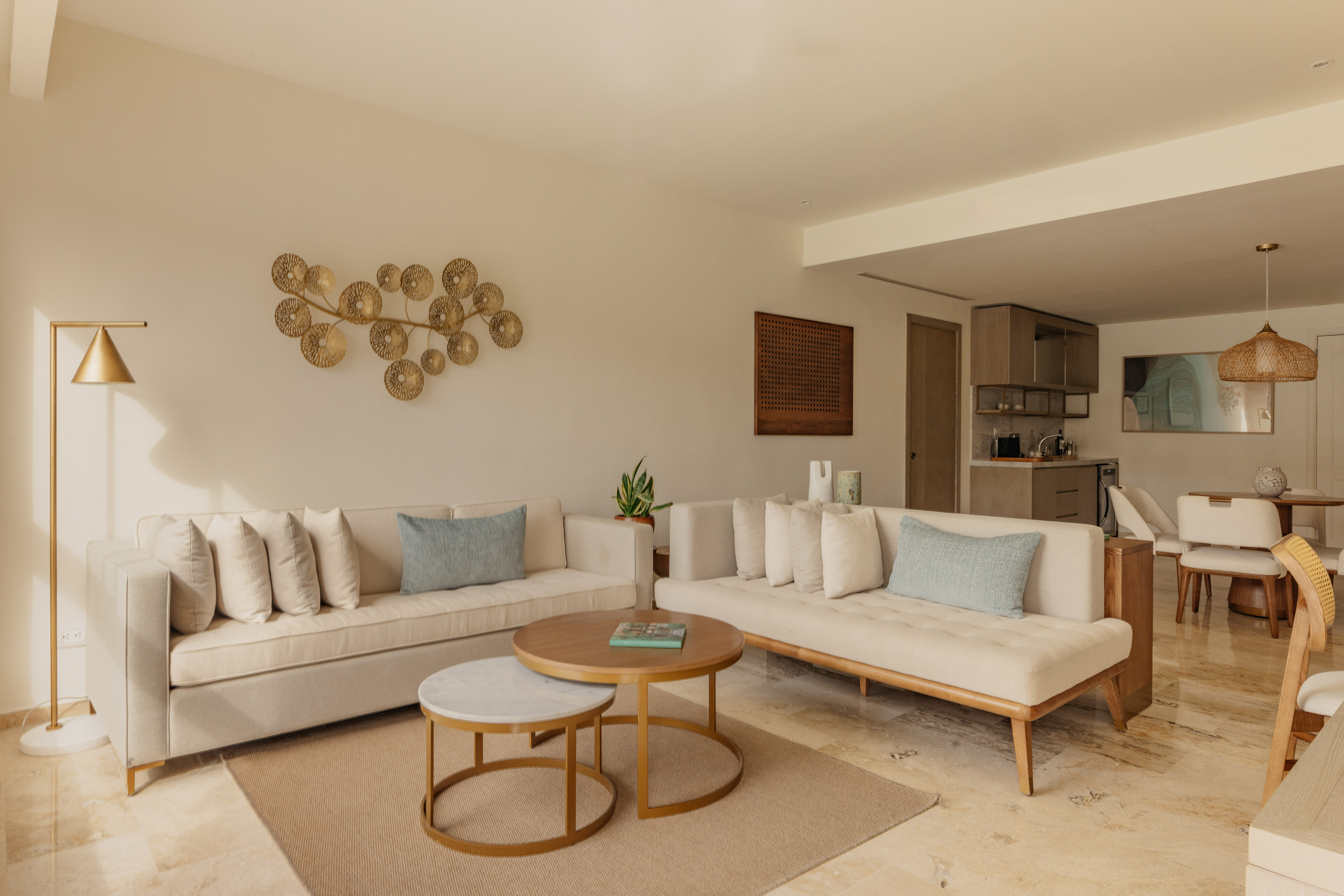 Modern living room with neutral sofas, nesting coffee tables, gold wall art.