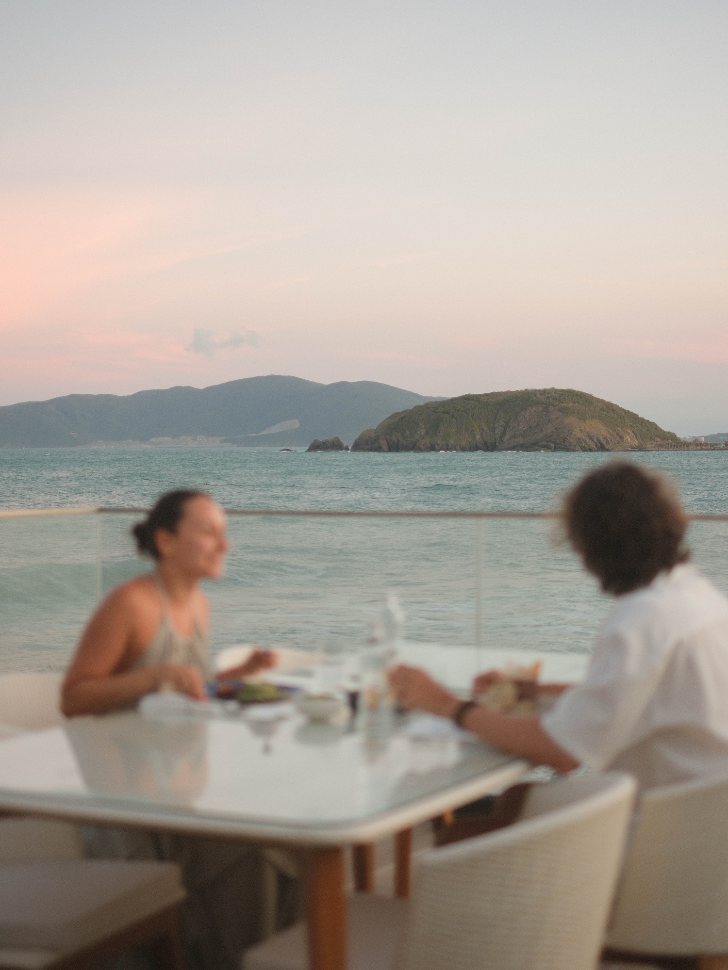 Oceanfront sunset dinner for two, with distant islands and mountains.
