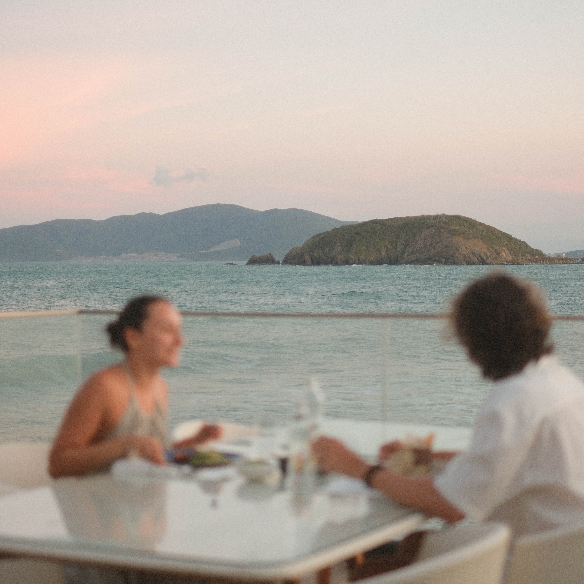 Oceanfront sunset dinner for two, with distant islands and mountains.