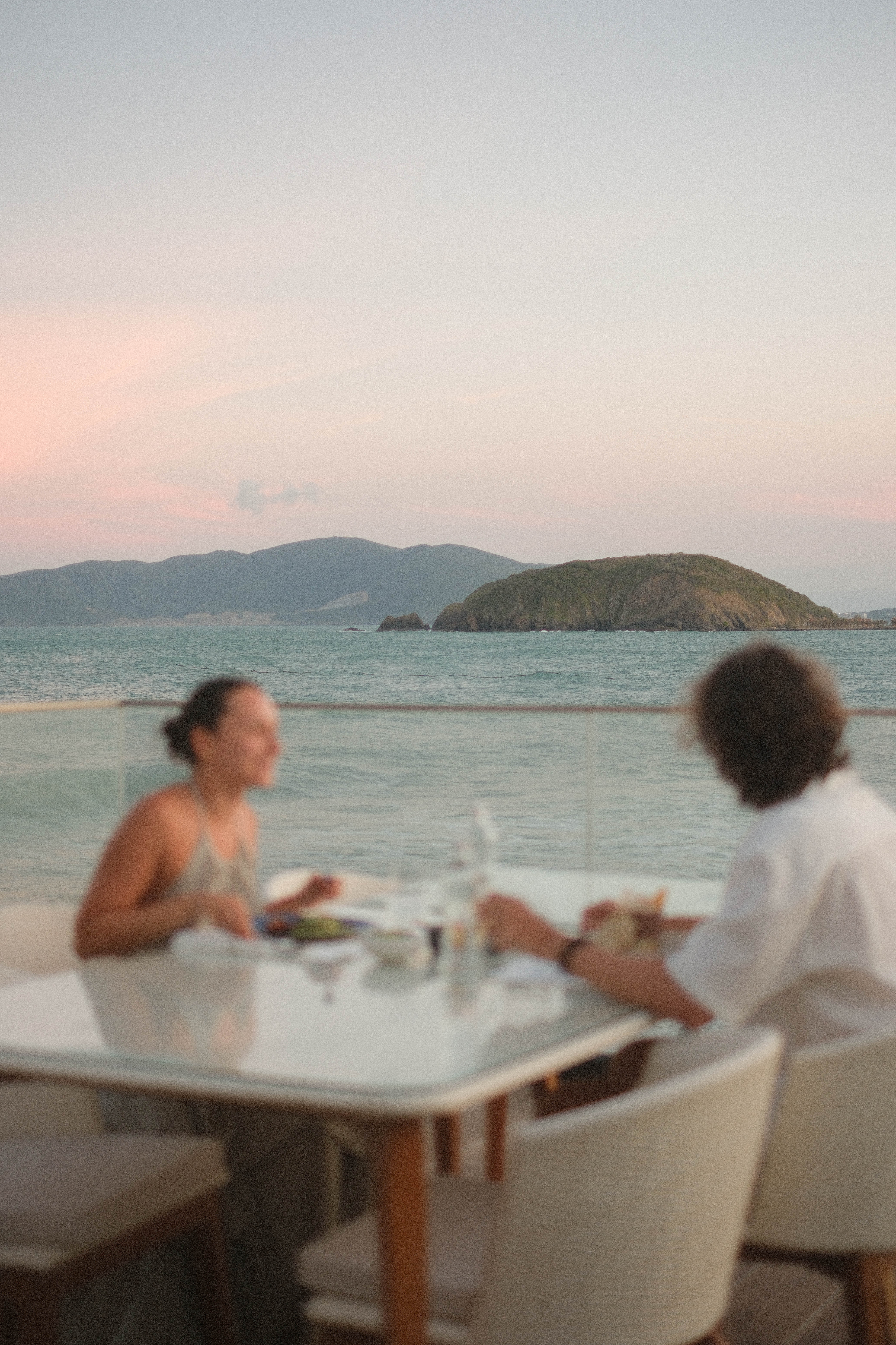 Oceanfront sunset dinner for two, with distant islands and mountains.