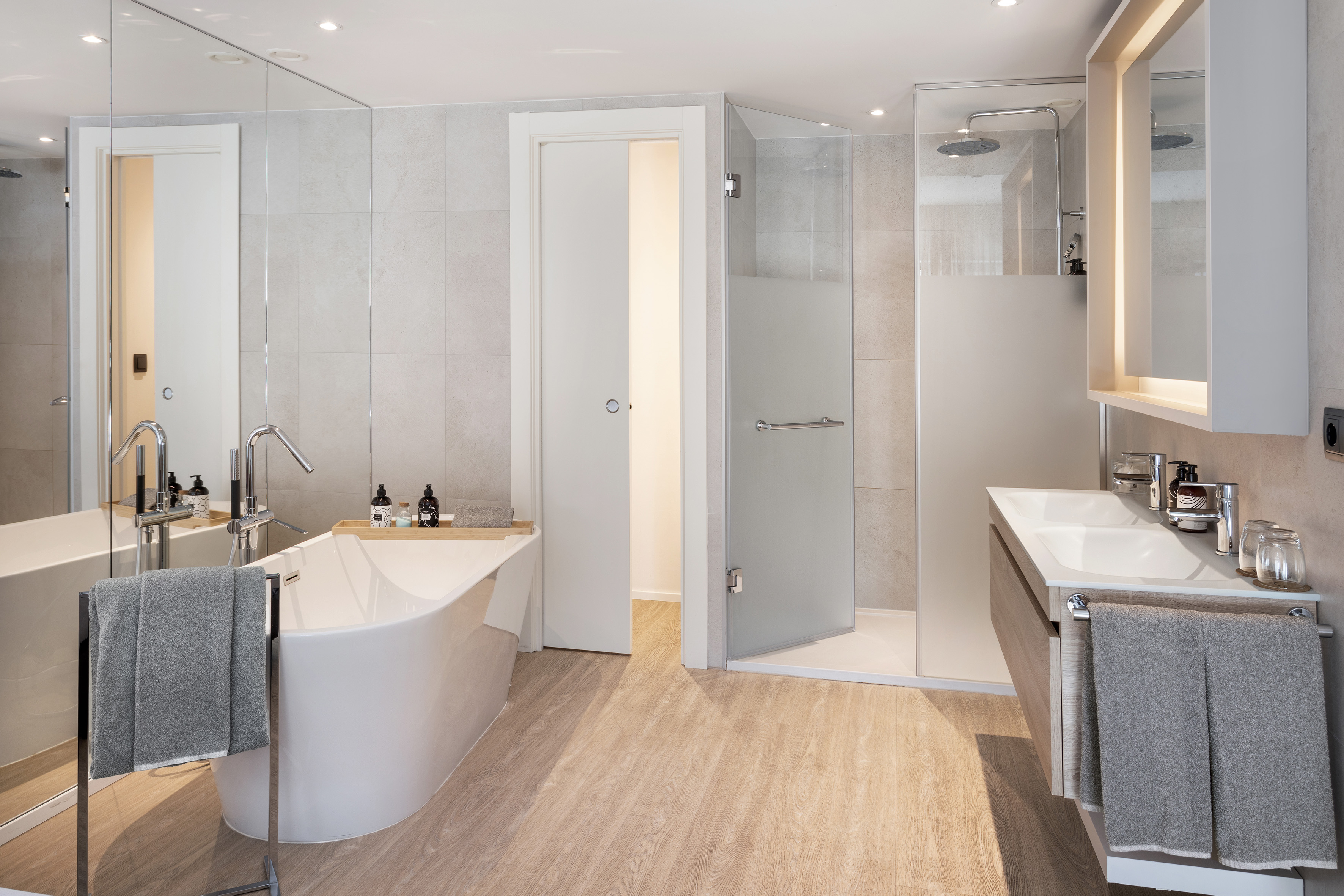 Modern bathroom with freestanding tub, walk-in shower, double vanity, and wood floor.