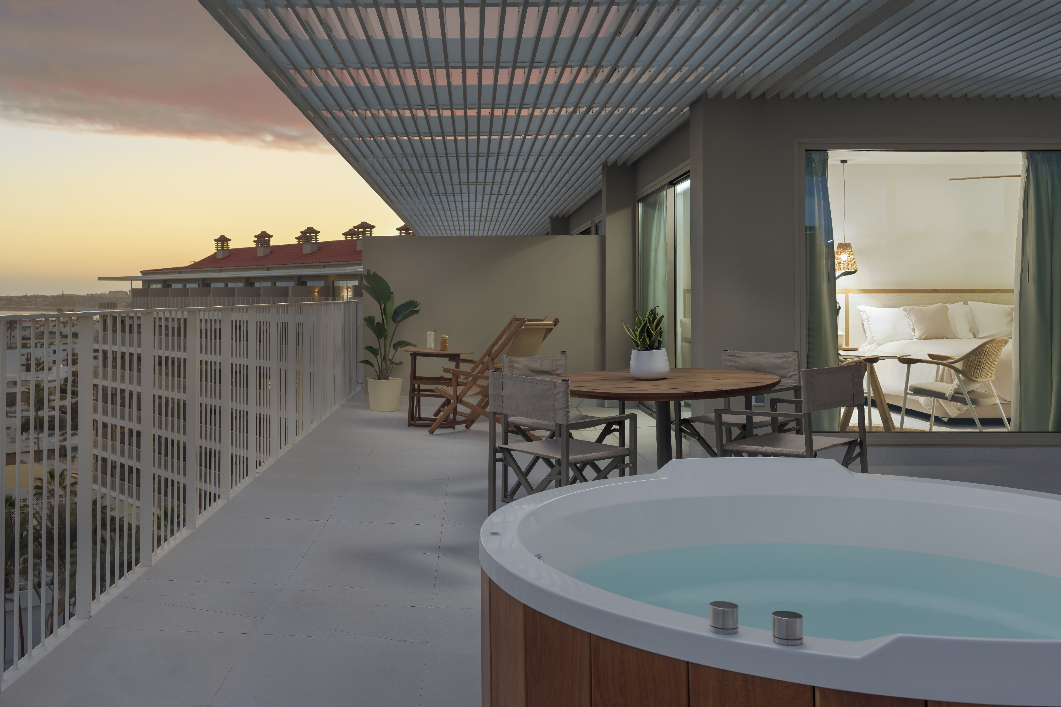 Private balcony with hot tub, outdoor seating, and sunset view.