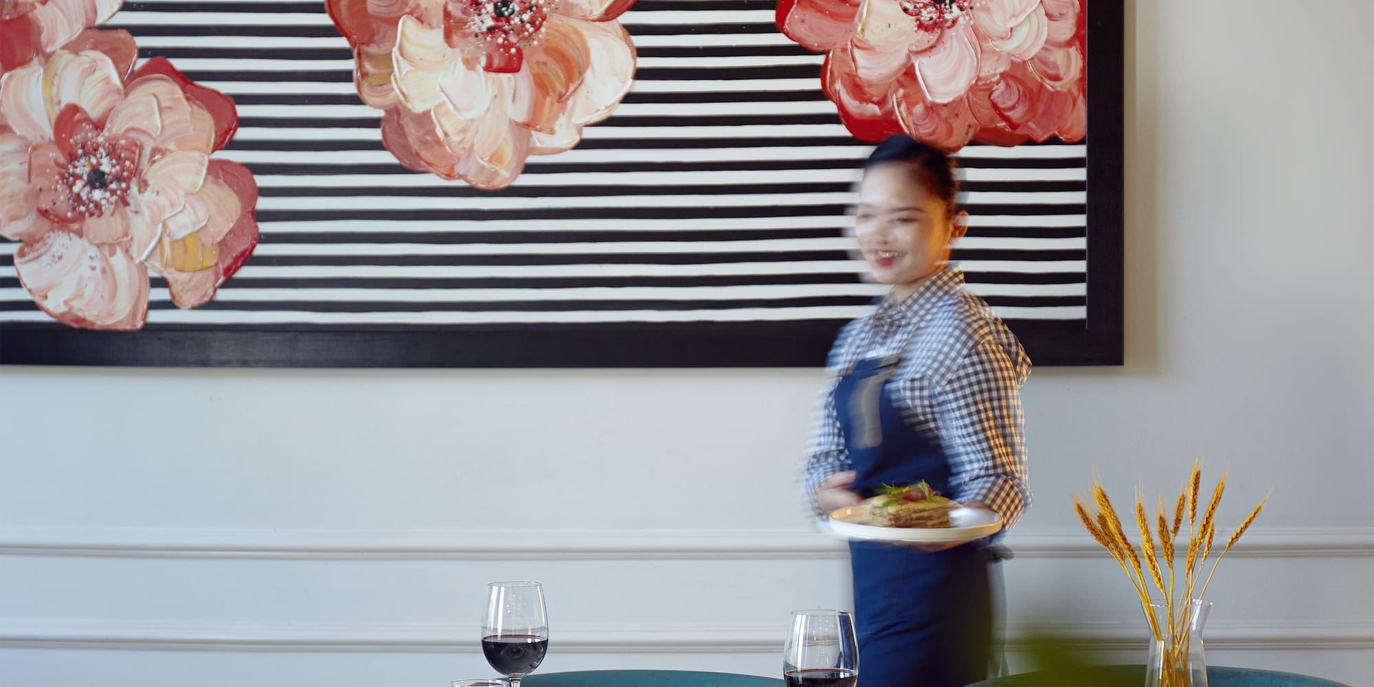 a woman holding a plate of food in front of a painting