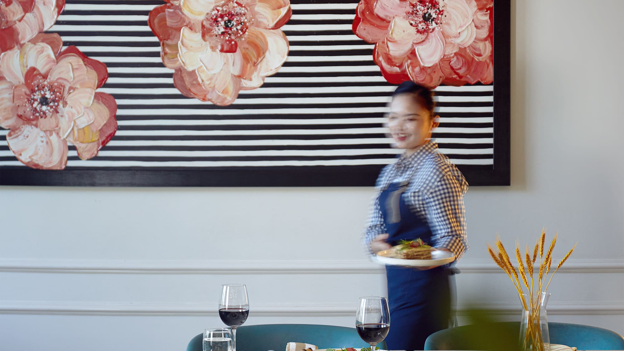 a woman holding a plate of food in front of a painting
