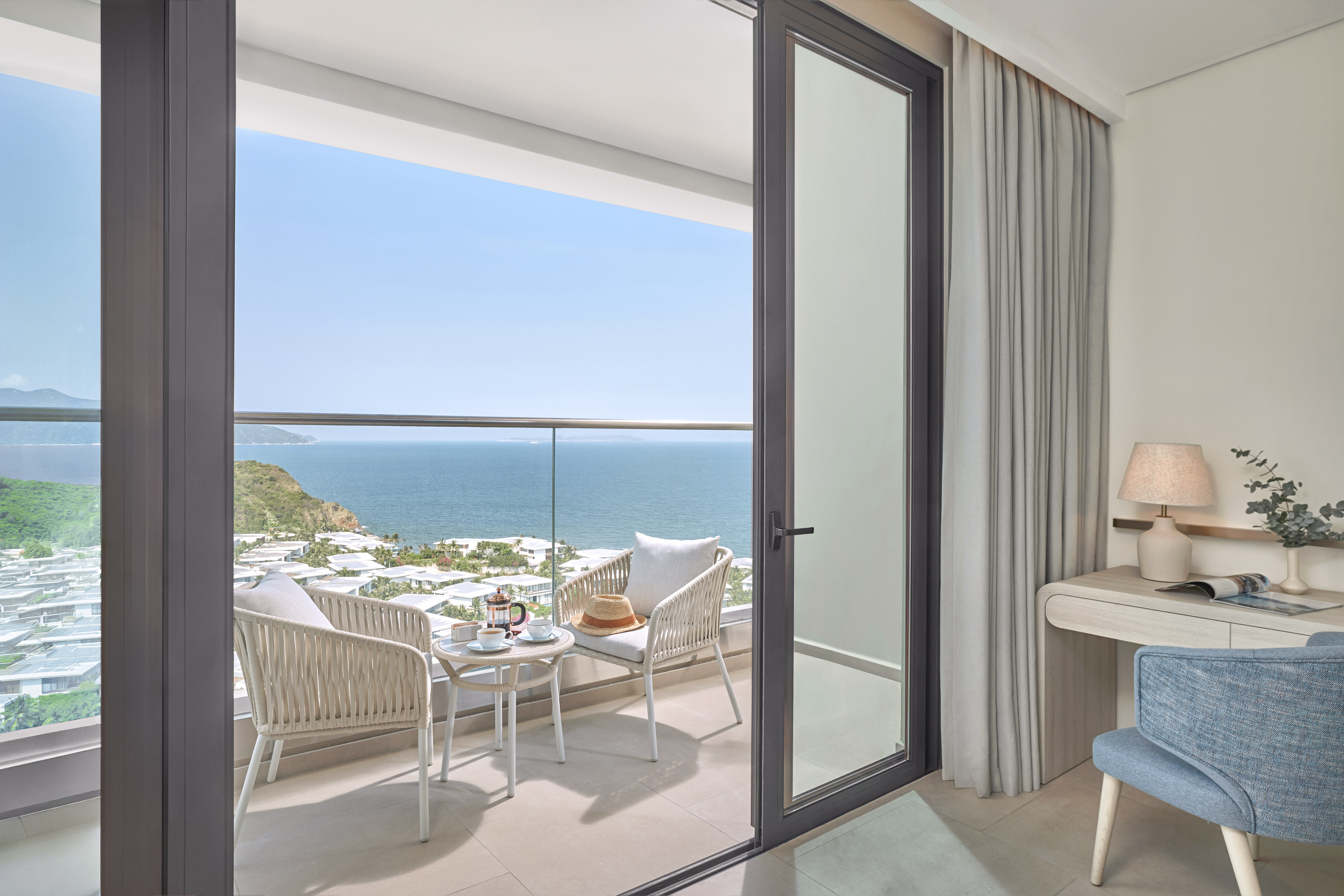 Ocean view balcony with outdoor seating, coffee, and a coastal resort landscape.