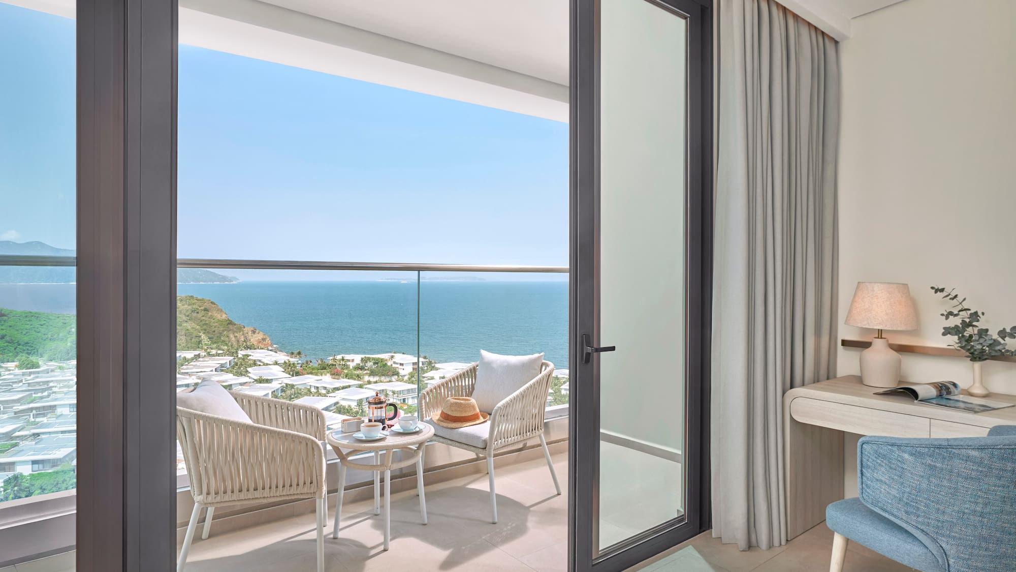 Ocean view balcony with outdoor seating, coffee, and a coastal resort landscape.