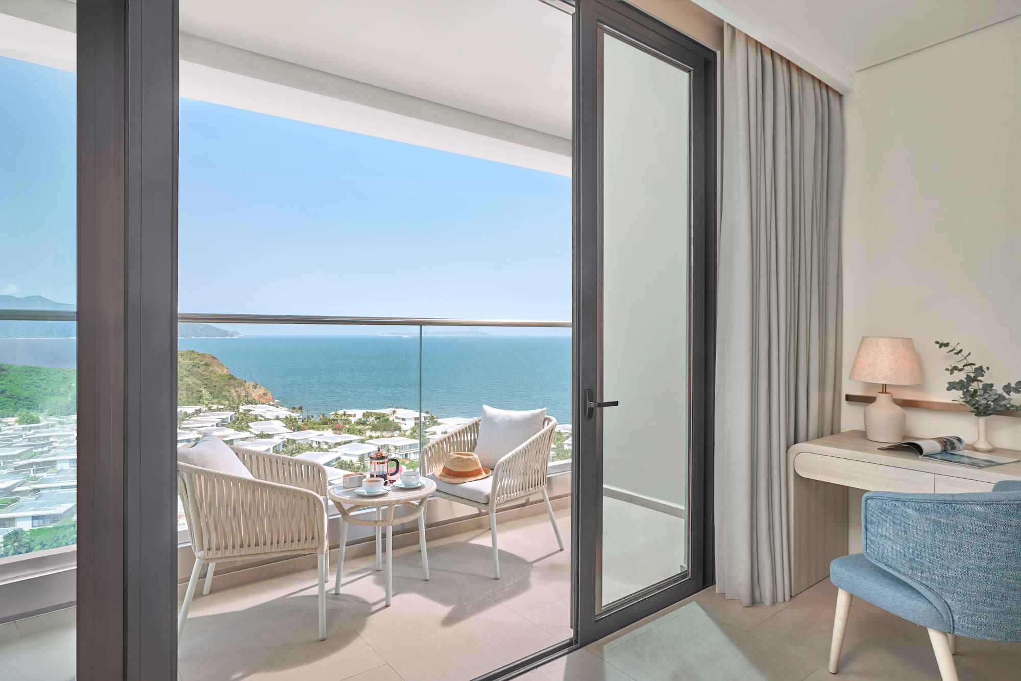 Ocean view balcony with outdoor seating, coffee, and a coastal resort landscape.