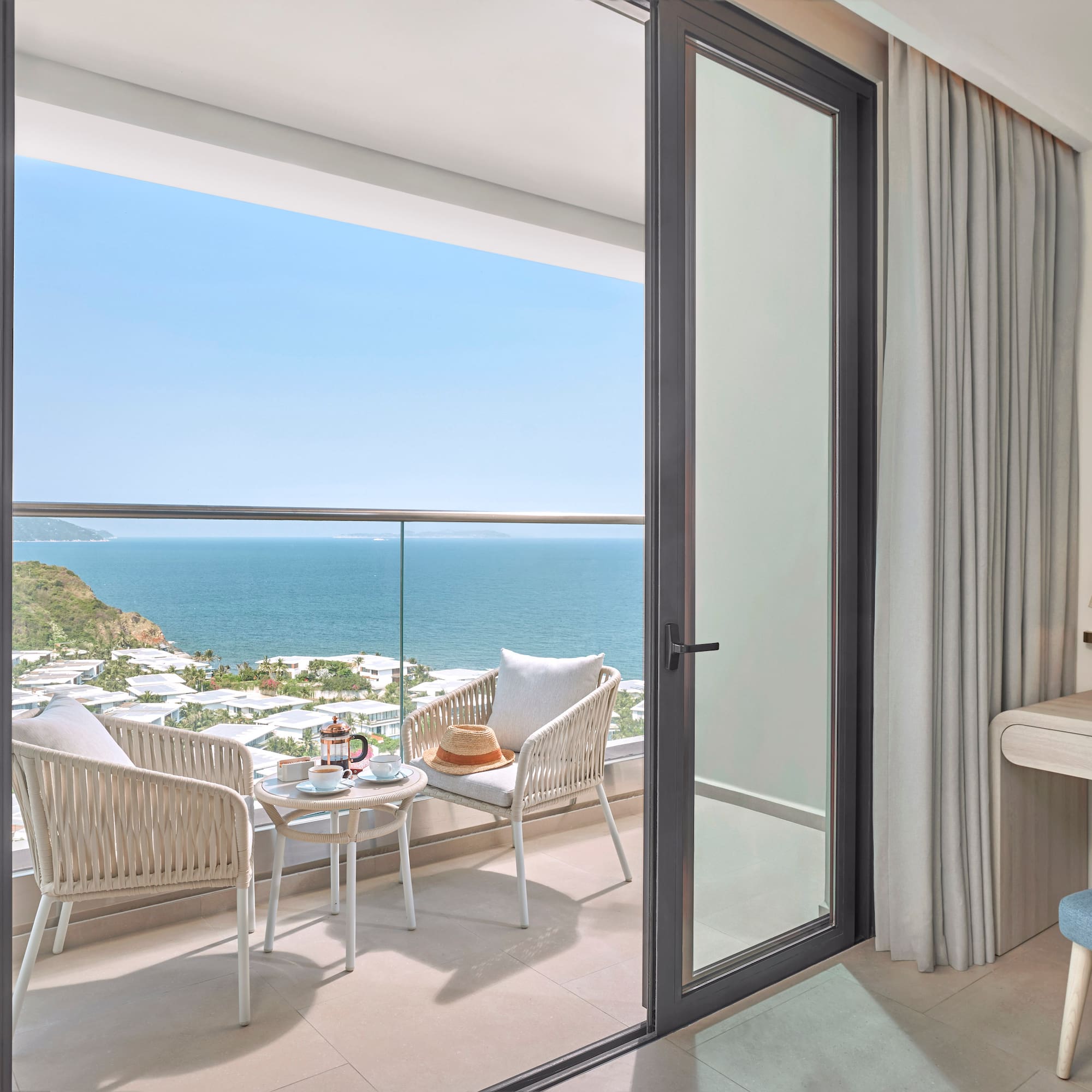 Ocean view balcony with outdoor seating, coffee, and a coastal resort landscape.