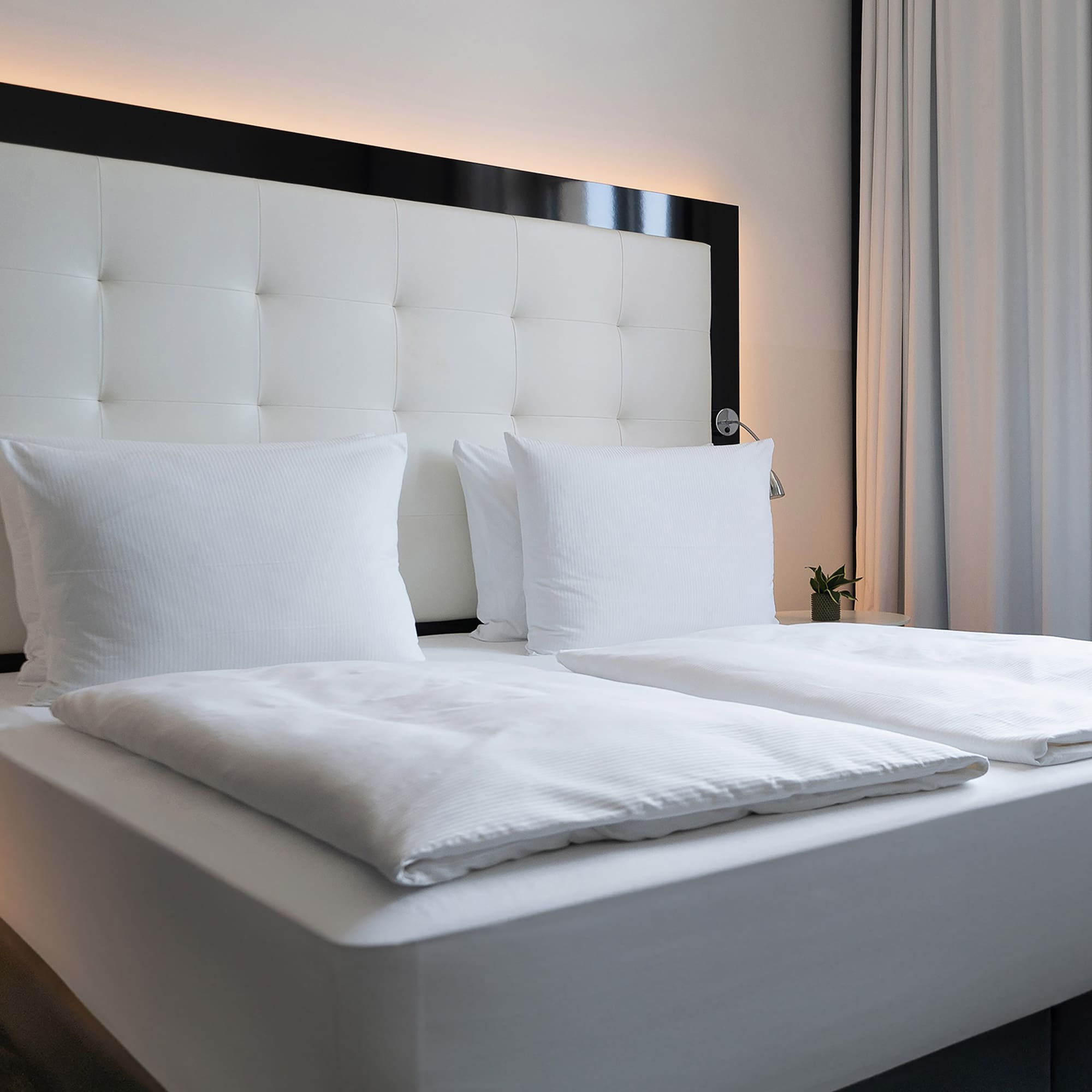 a bed with white sheets and pillows