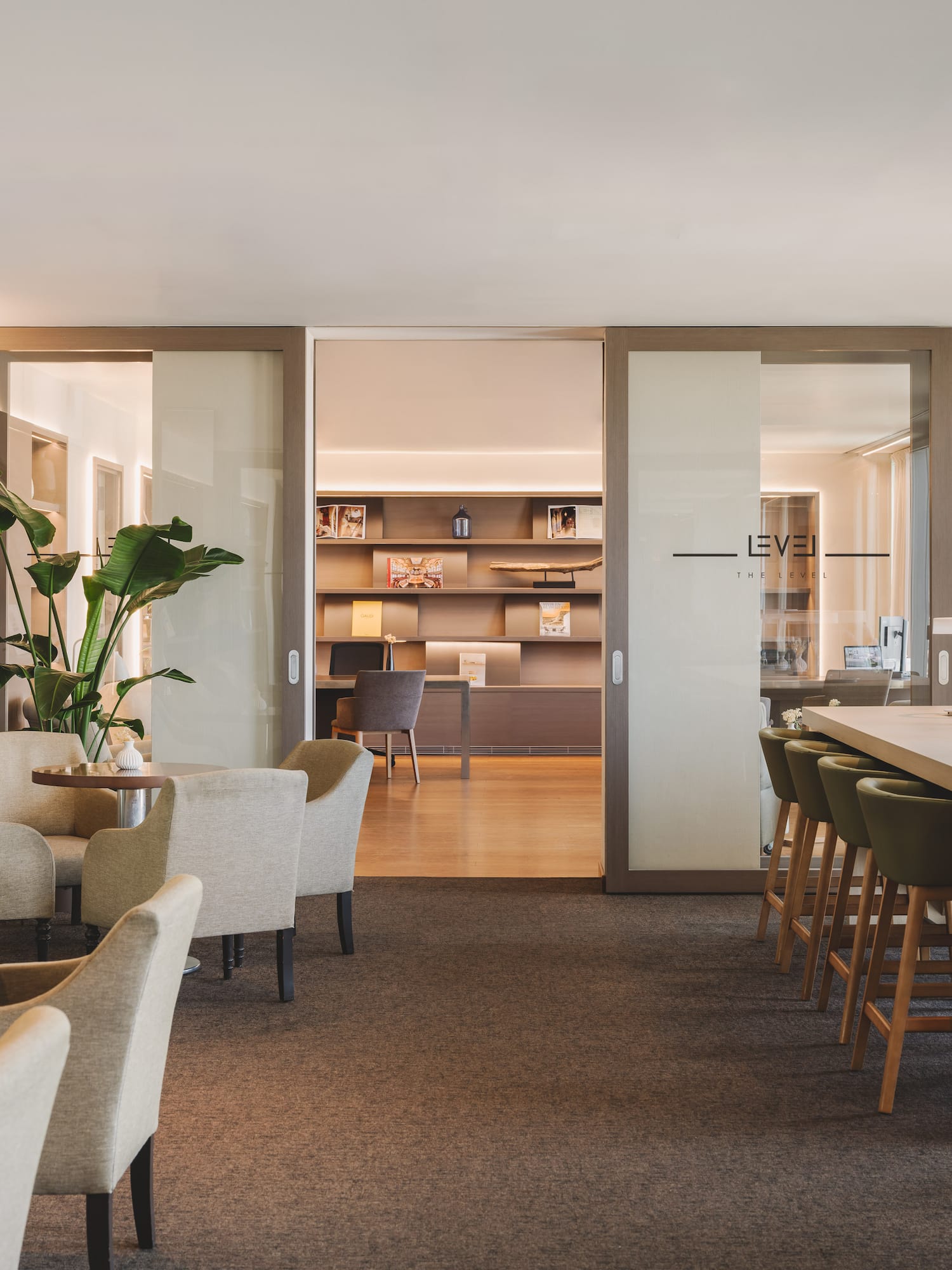 Modern 'The Level' lounge with armchairs, communal table, and bookshelves.