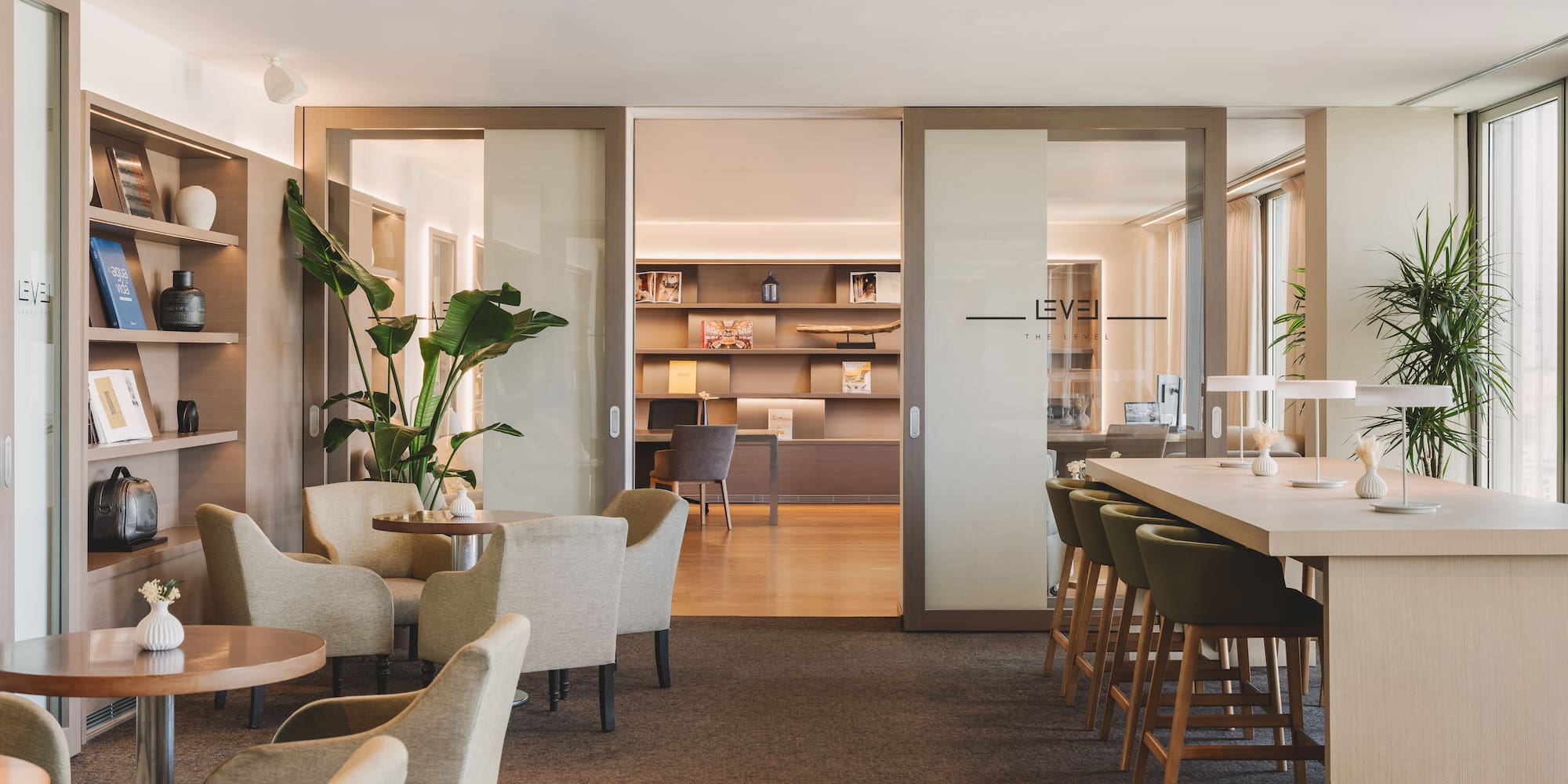 Lounge moderno de oficina/hotel con asientos, barra y estanterías.