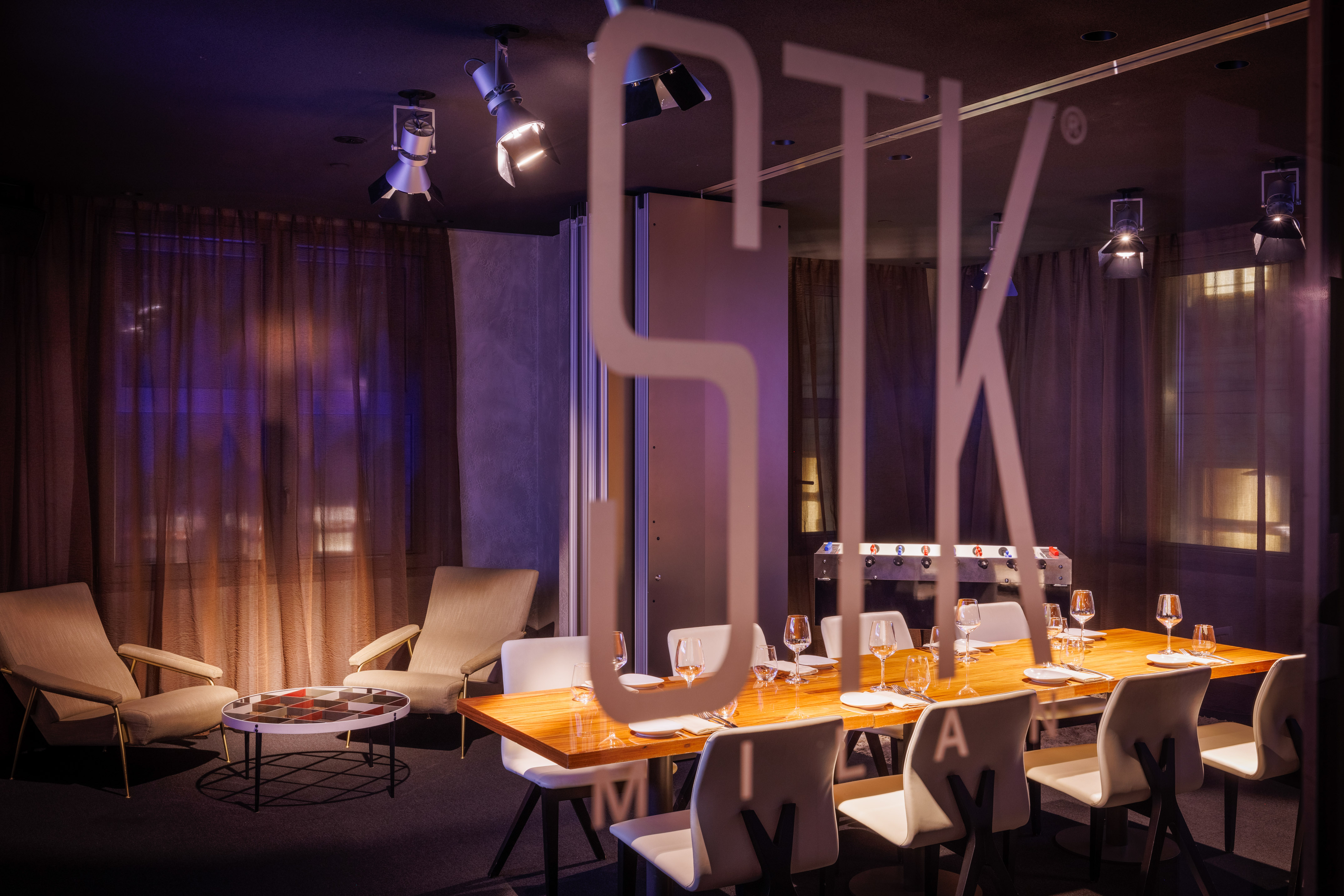 Modern STK private dining with wooden table, lounge seating, and foosball.