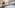 Modern hotel suite with bed, sofa, TV, yoga mat, and city skyline view.