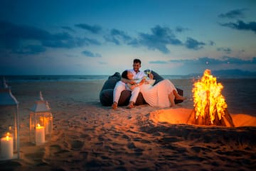 a man and woman sitting on a bean bag chair on a beach
