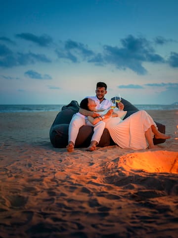 a man and woman sitting on a bean bag chair on a beach