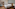 Modern luxury hotel bedroom with large bed, wood floor, and en-suite bathroom.