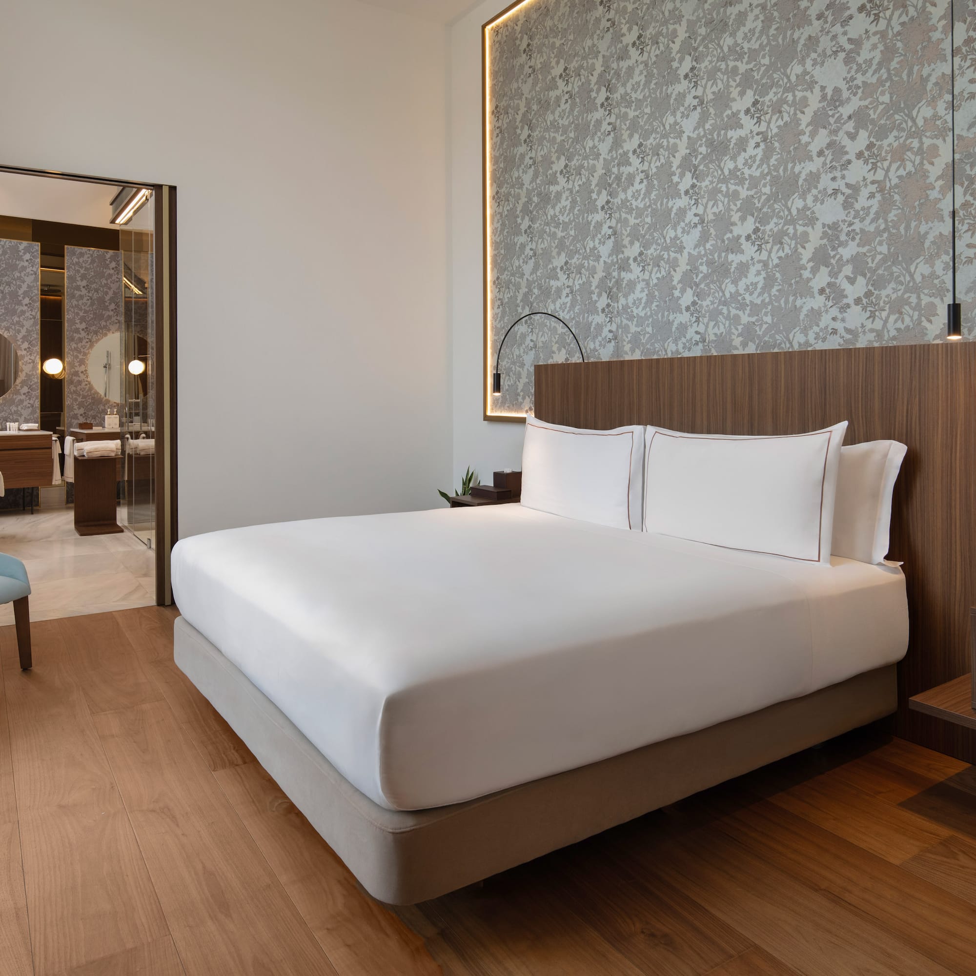 Modern luxury hotel bedroom with large bed, wood floor, and en-suite bathroom.
