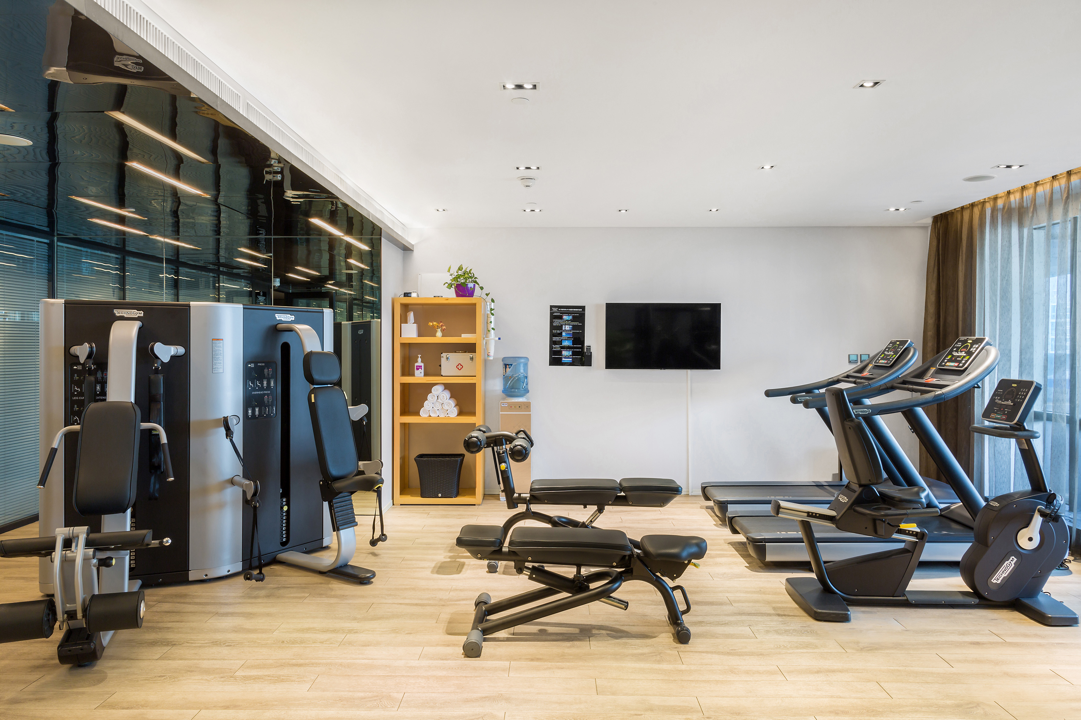 Bright, modern gym with treadmills, weight machine, and strength equipment.