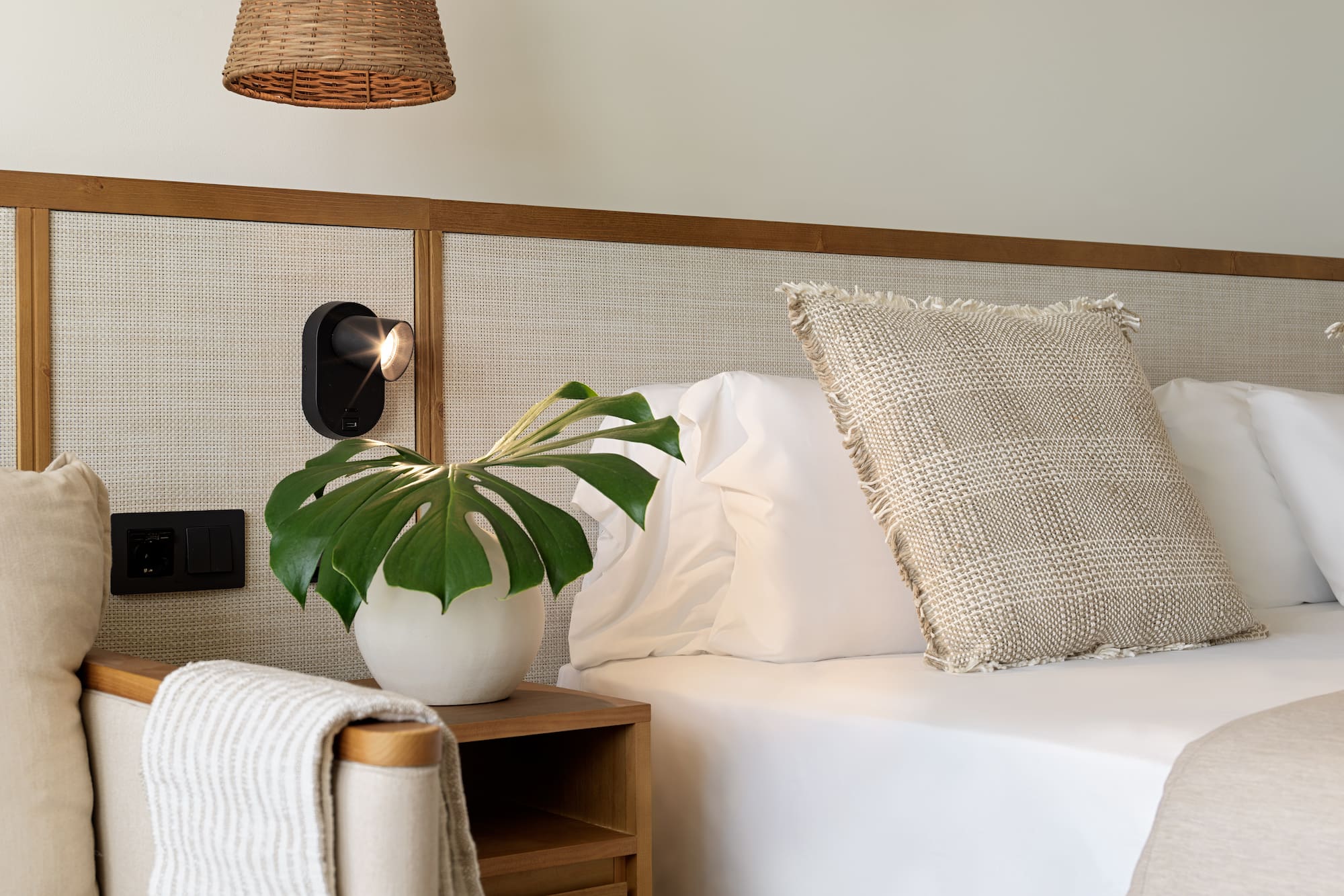 a plant on a table next to a bed