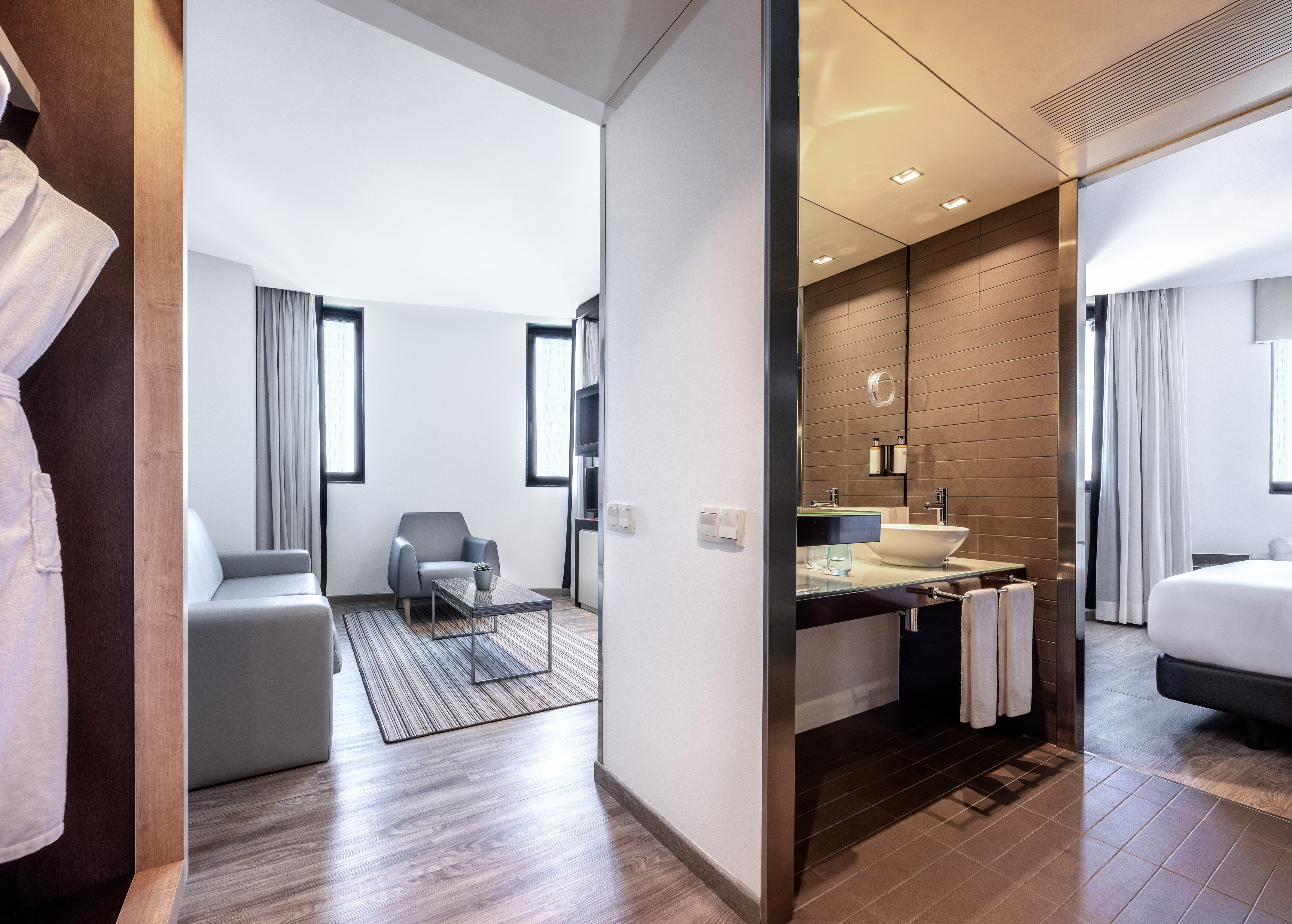 Spacious modern hotel suite: living area, stylish bathroom, and bedroom.