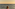 Woman in striped swimsuit on boat, looking at ocean sunset.