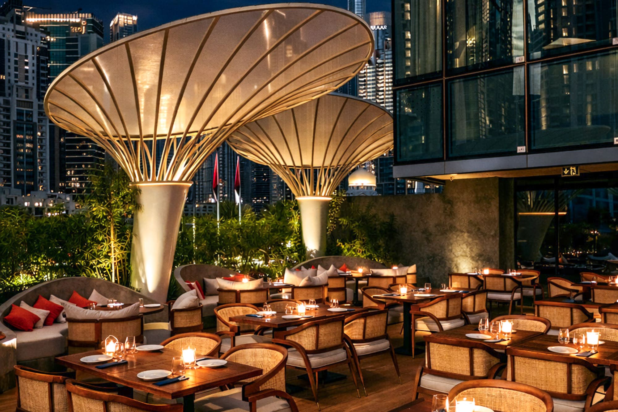 Dubai outdoor restaurant with Burj Khalifa view at night, candlelit tables.