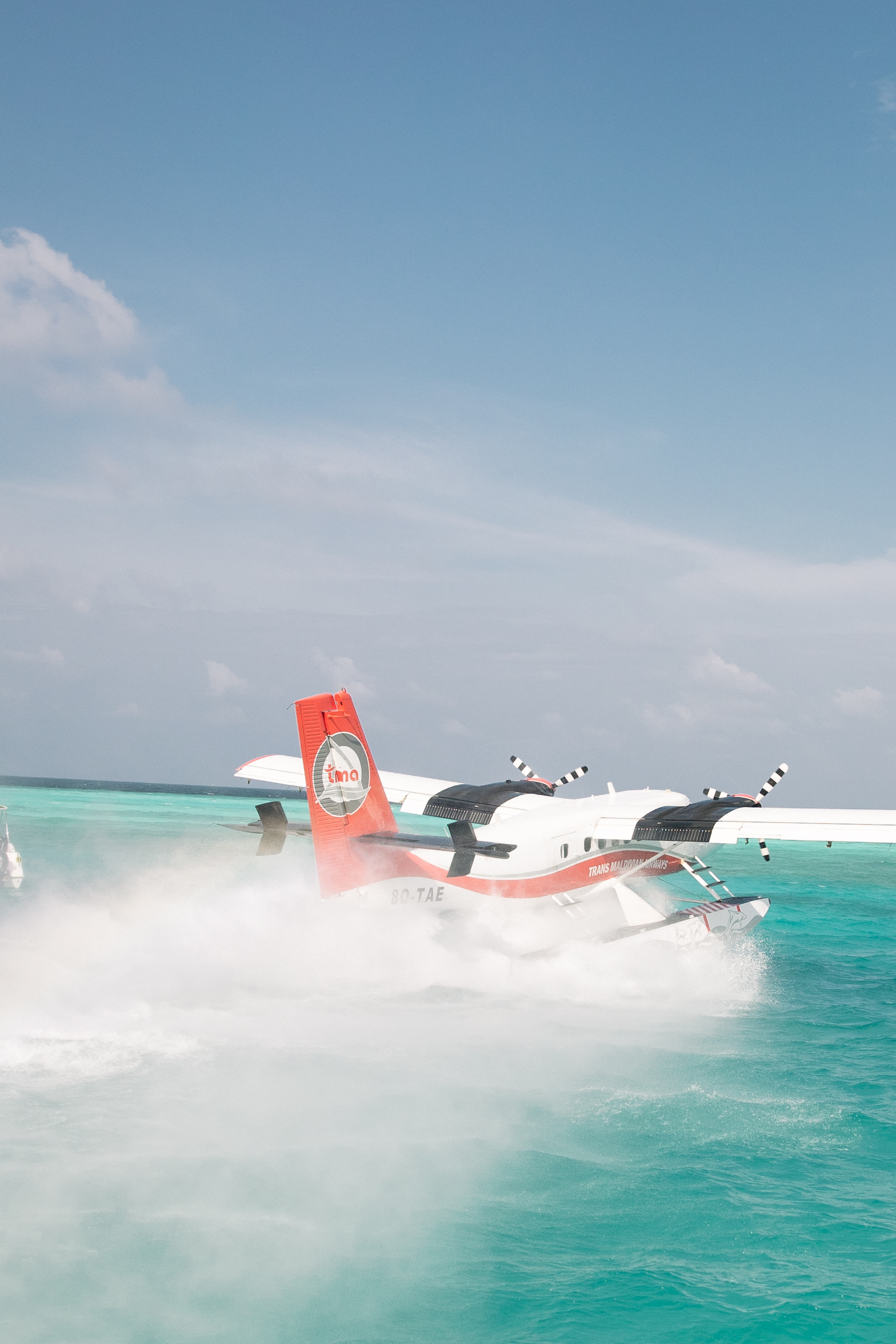 Trans Maldivian seaplane splashing on turquoise water in Maldives.