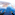 Feet dangling high above vast blue ocean and rugged islands, aerial perspective.