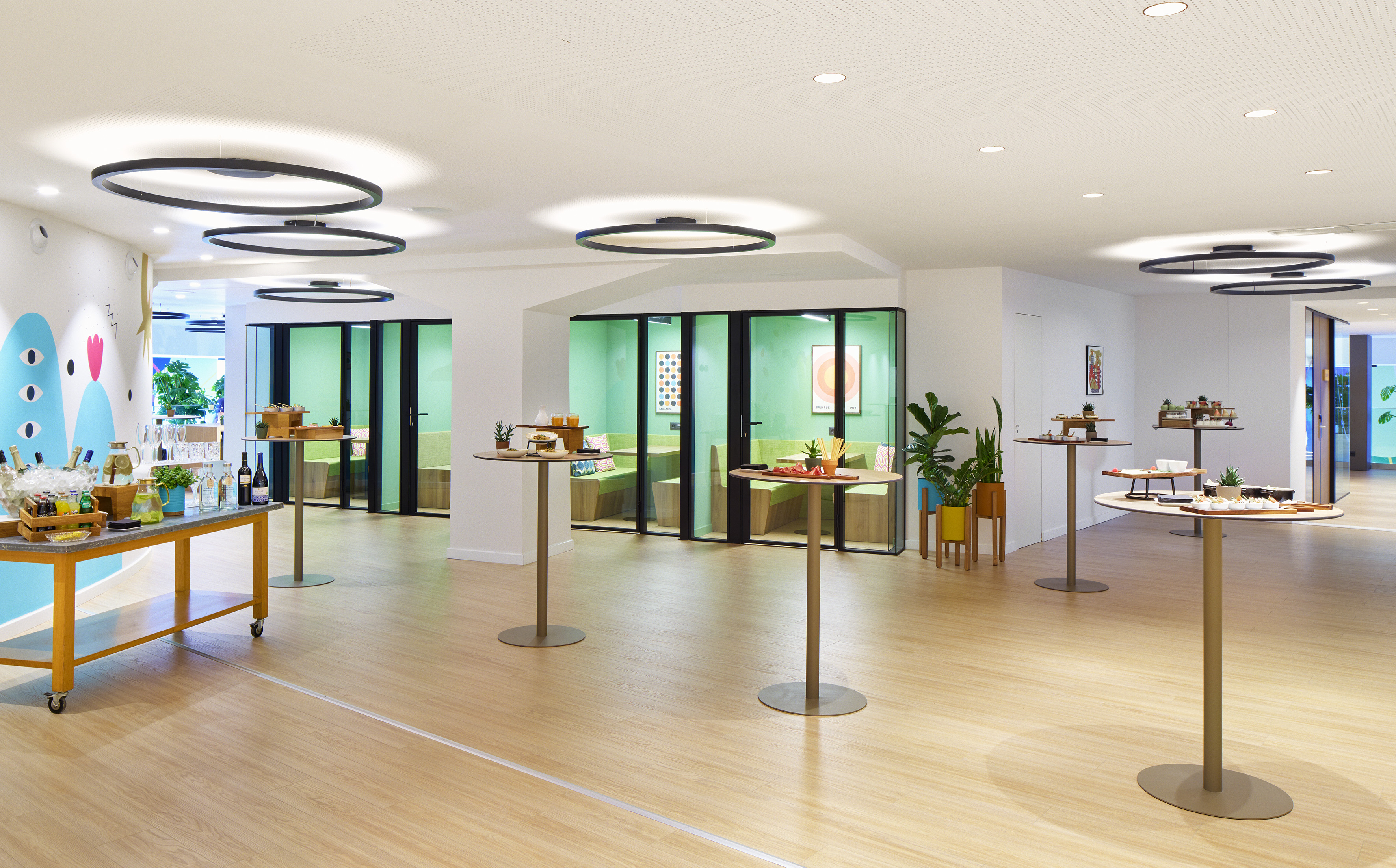 Modern event space with buffet catering, high tables, and green glass rooms.