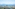 Balcony sea view of coastal buildings, distant mountains, and a tall pine tree.