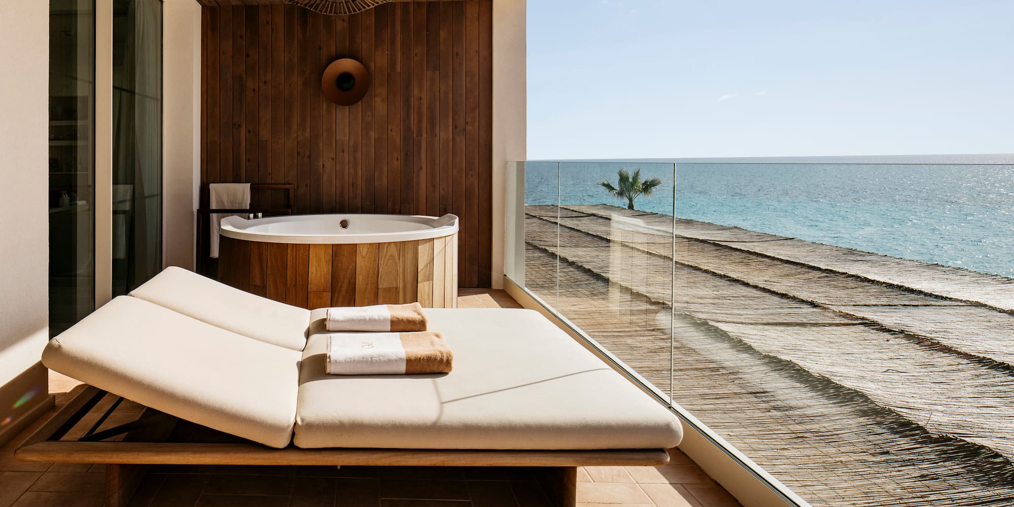a deck with a tub and a hot tub overlooking the ocean