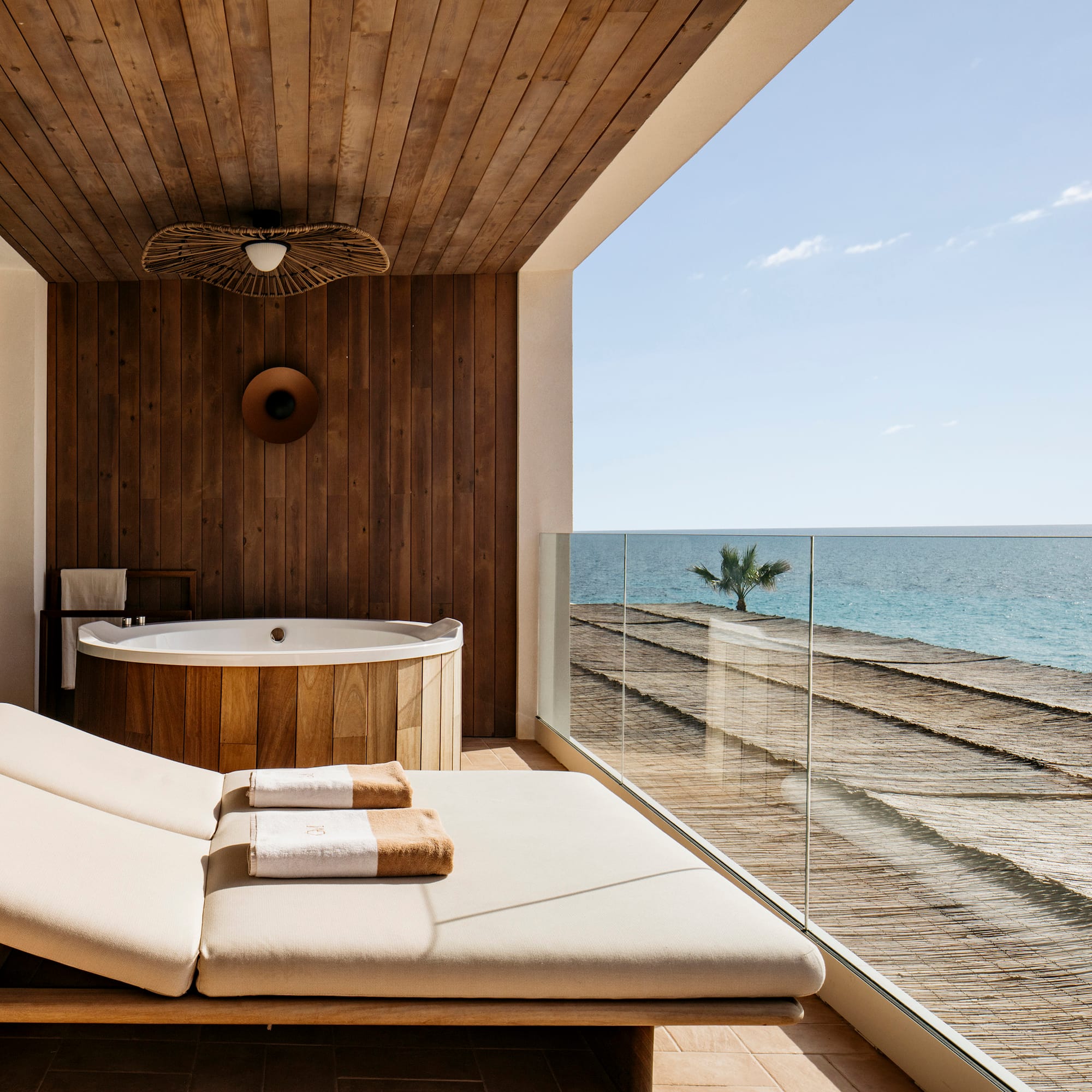 a deck with a tub and a hot tub overlooking the ocean