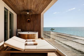a deck with a tub and a hot tub overlooking the ocean