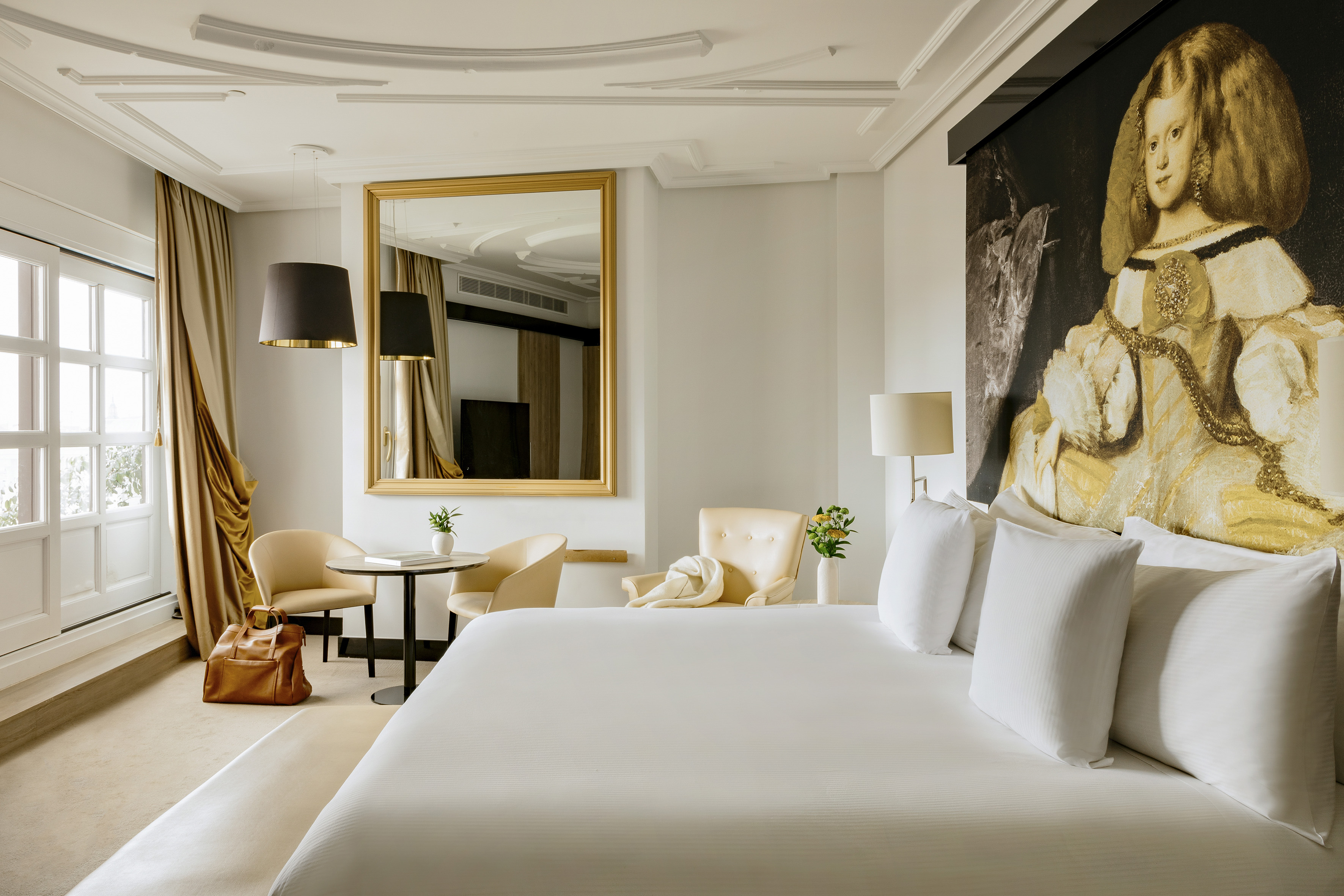 Velázquez-style portrait art in a luxurious hotel suite with large bed.