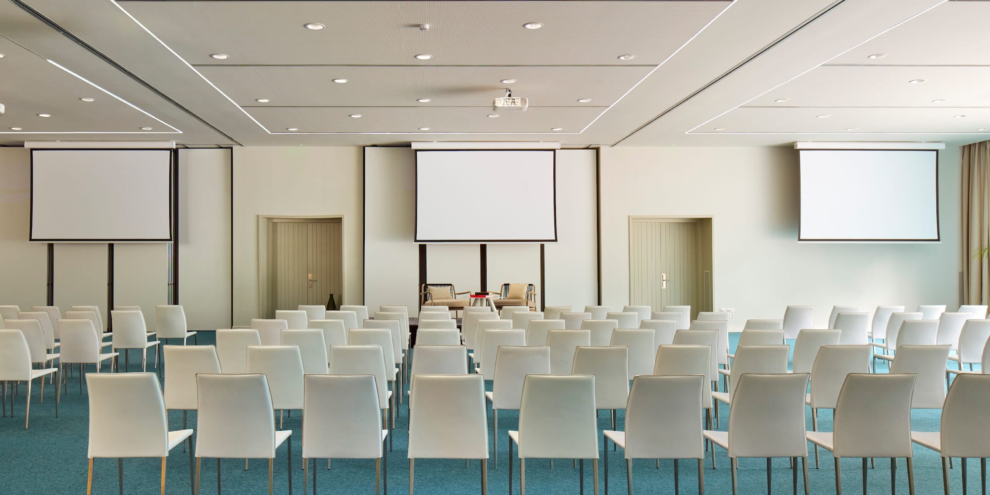 a room with white chairs and a projector screen