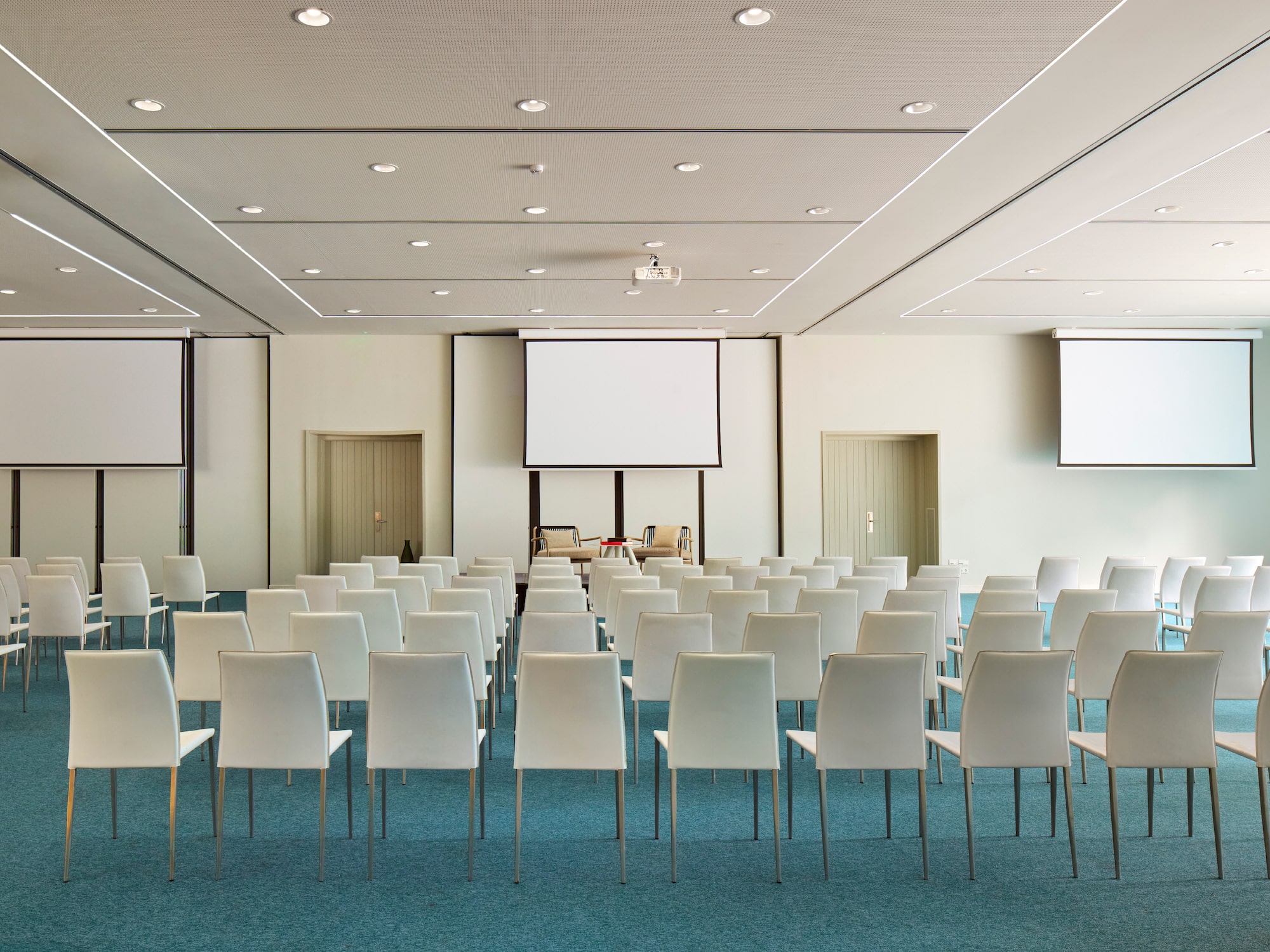 a room with white chairs and a projector screen