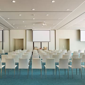 a room with white chairs and a projector screen